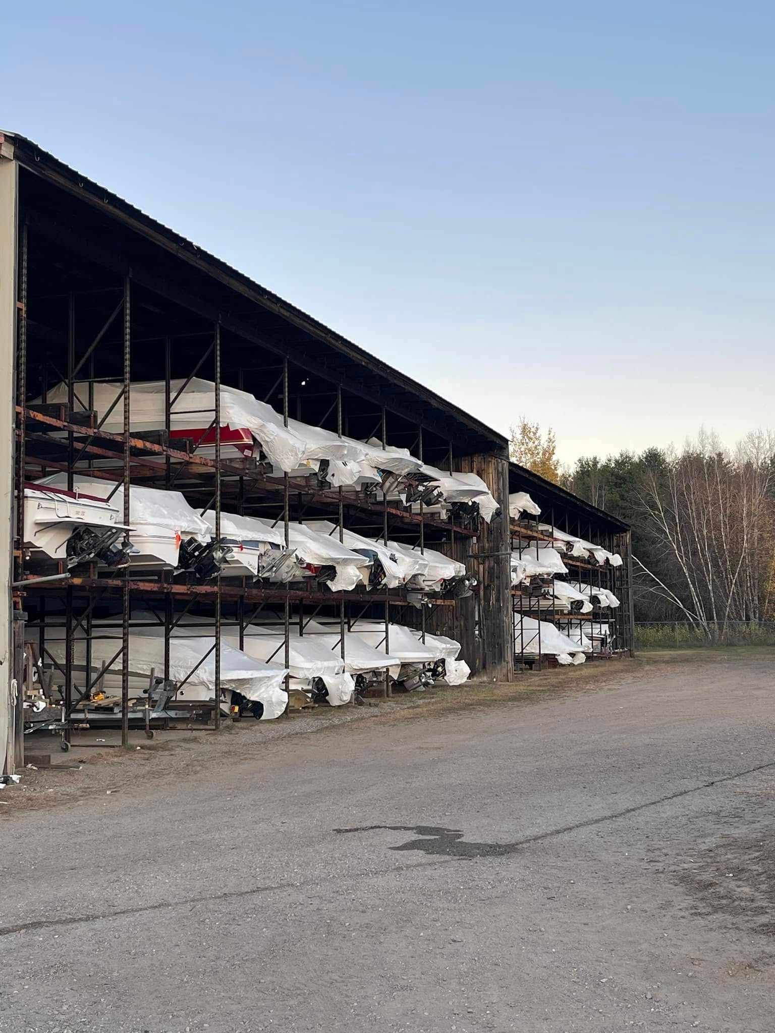 A row of boats are stacked on top of each other in a warehouse.