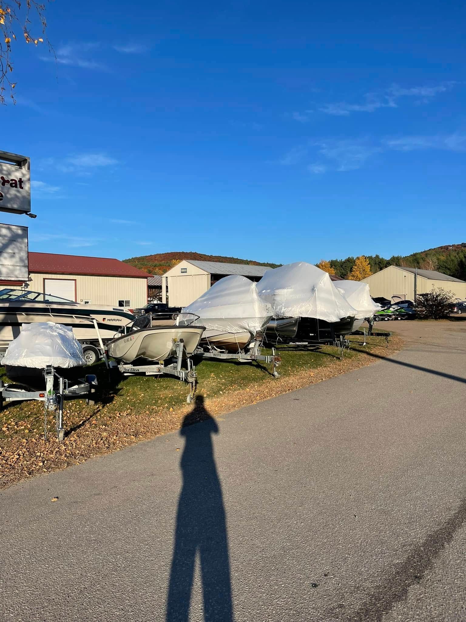 A row of white boats are parked in a parking lot.