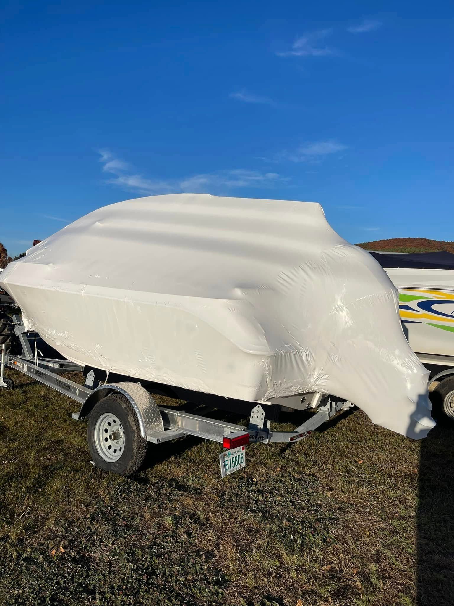 A boat is wrapped in plastic and sitting on a trailer.