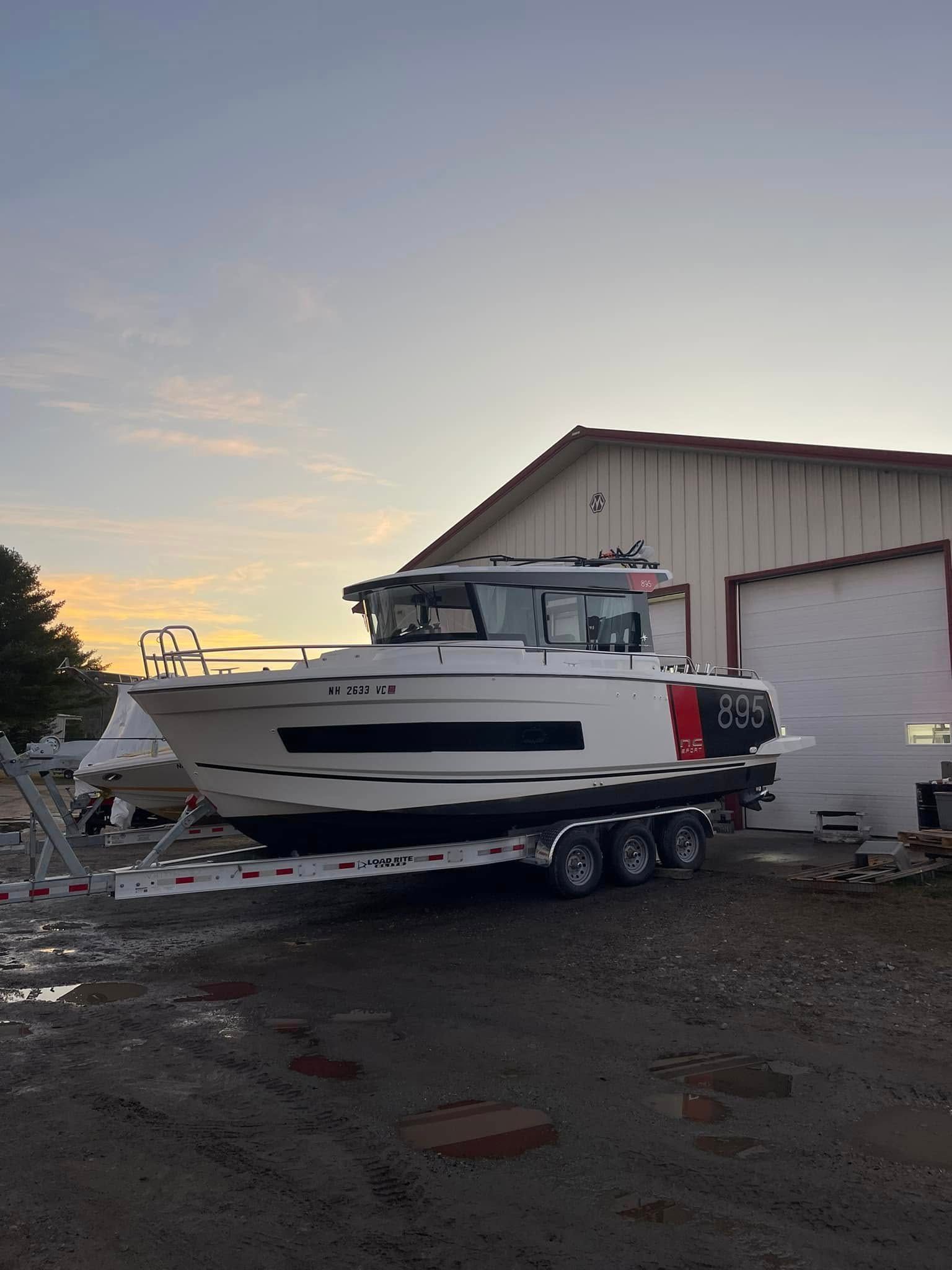 A boat on a trailer is parked in front of a building.