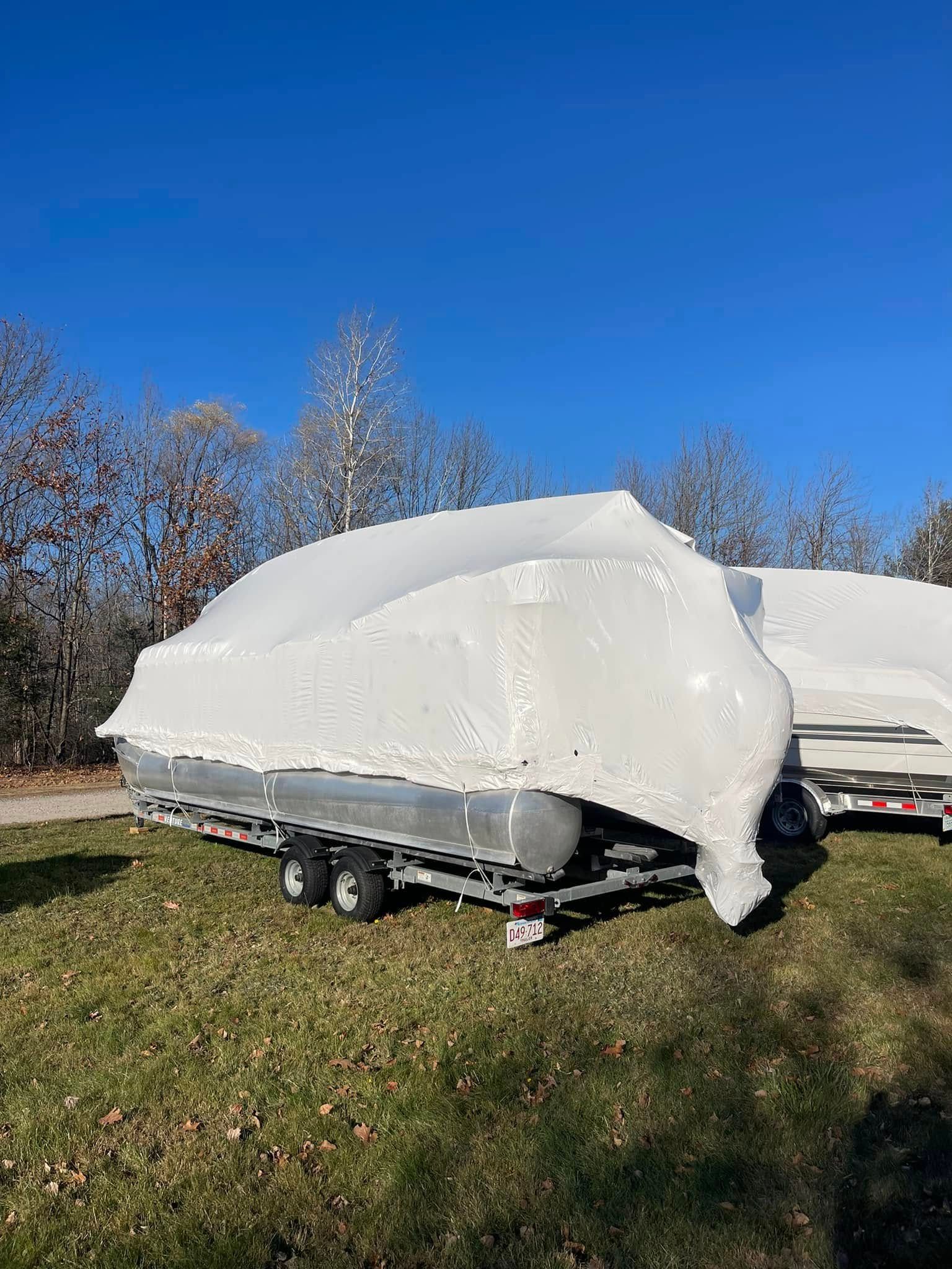 A boat is wrapped in plastic and sitting on top of a trailer.