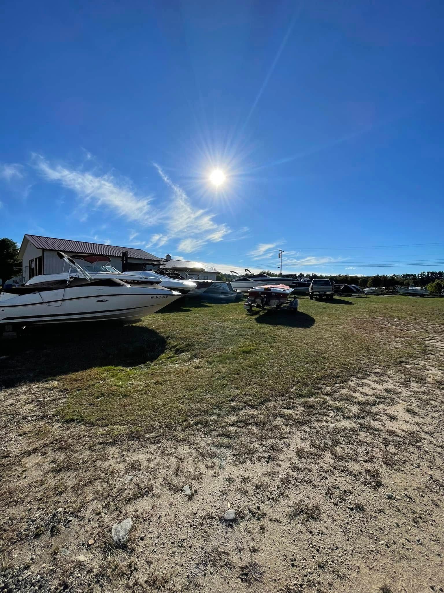 A group of boats are parked in a field on a sunny day.