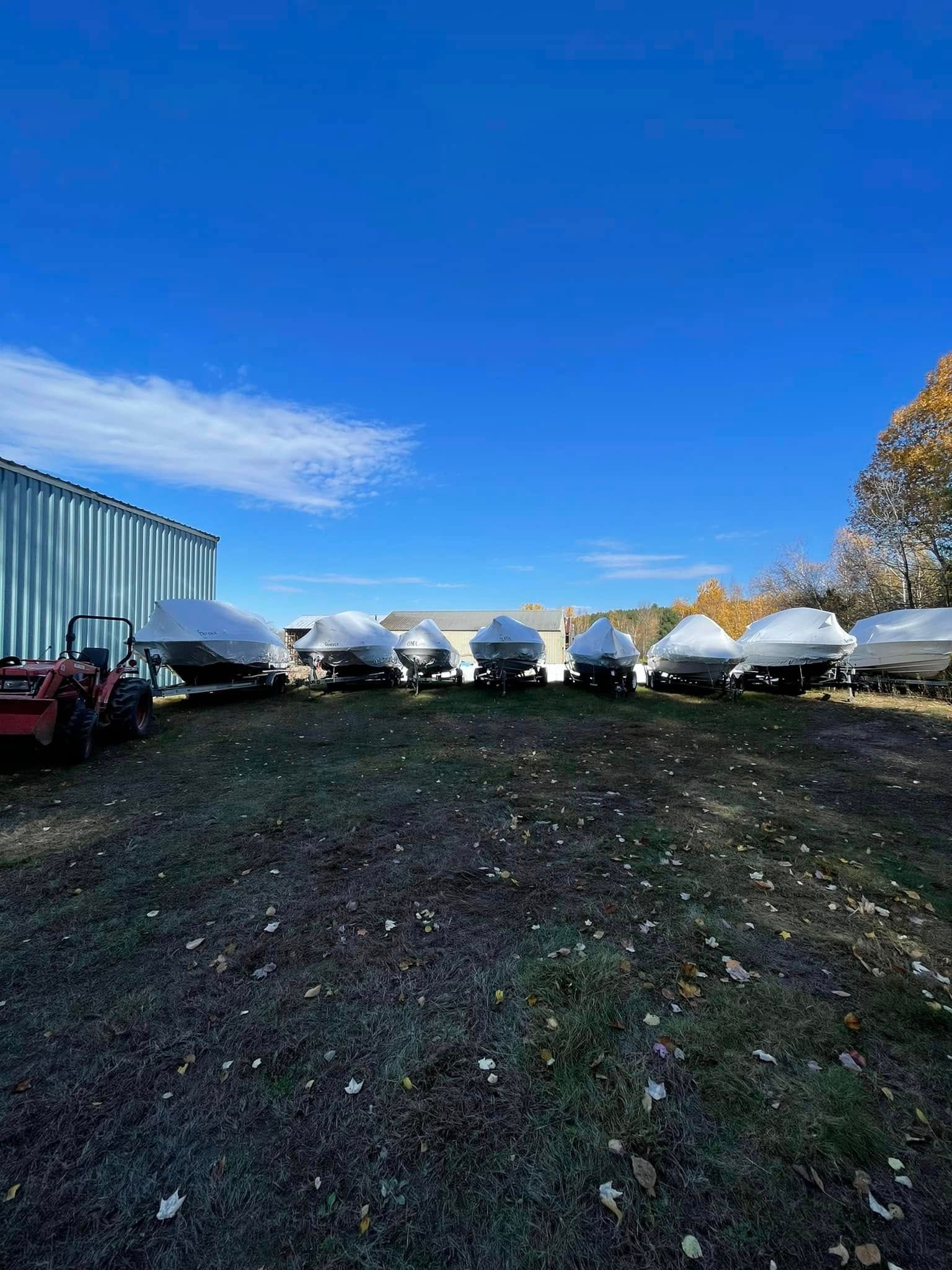 A row of boats are parked in a grassy field.