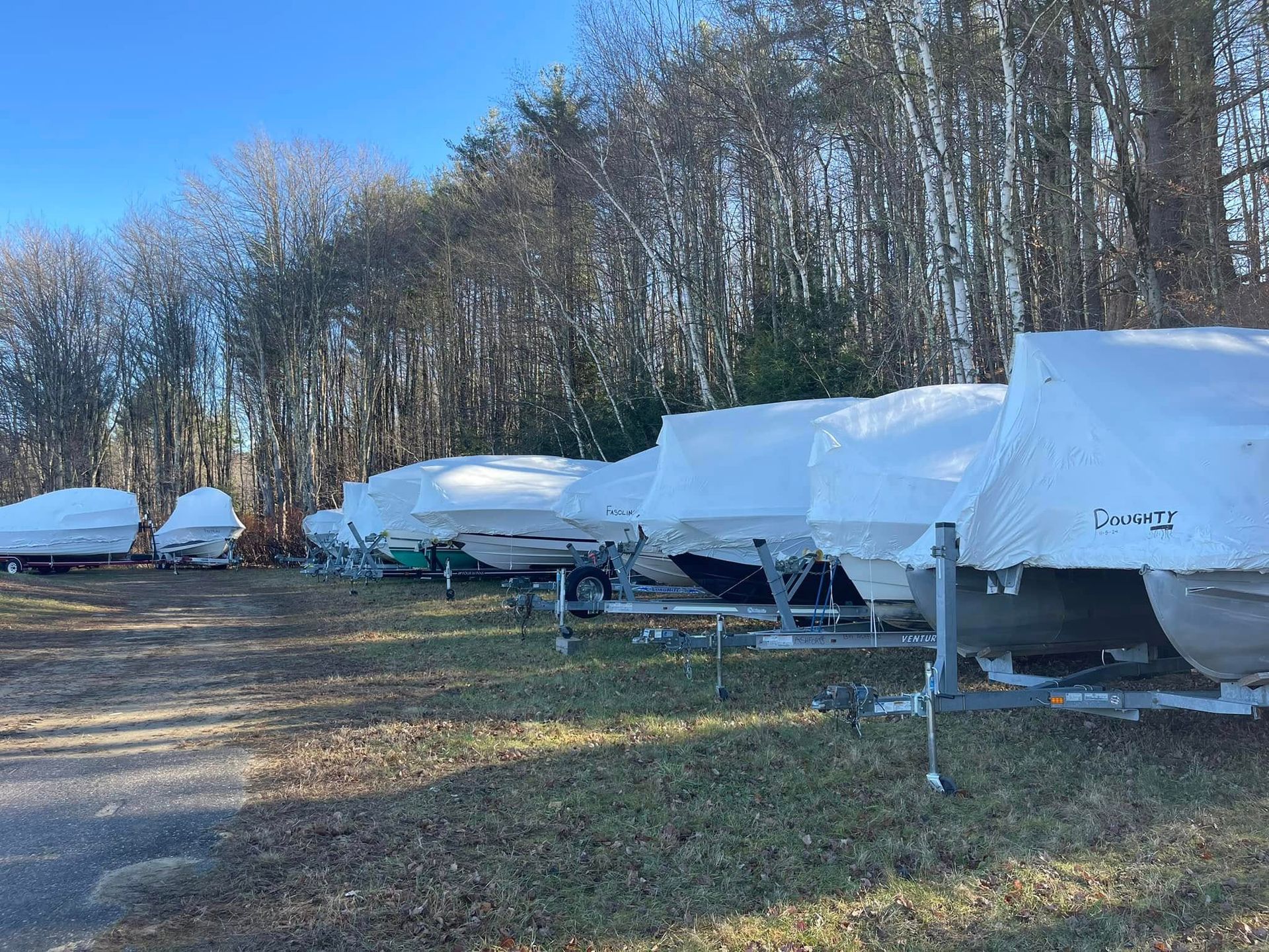 A row of boats are covered in snow in a field.