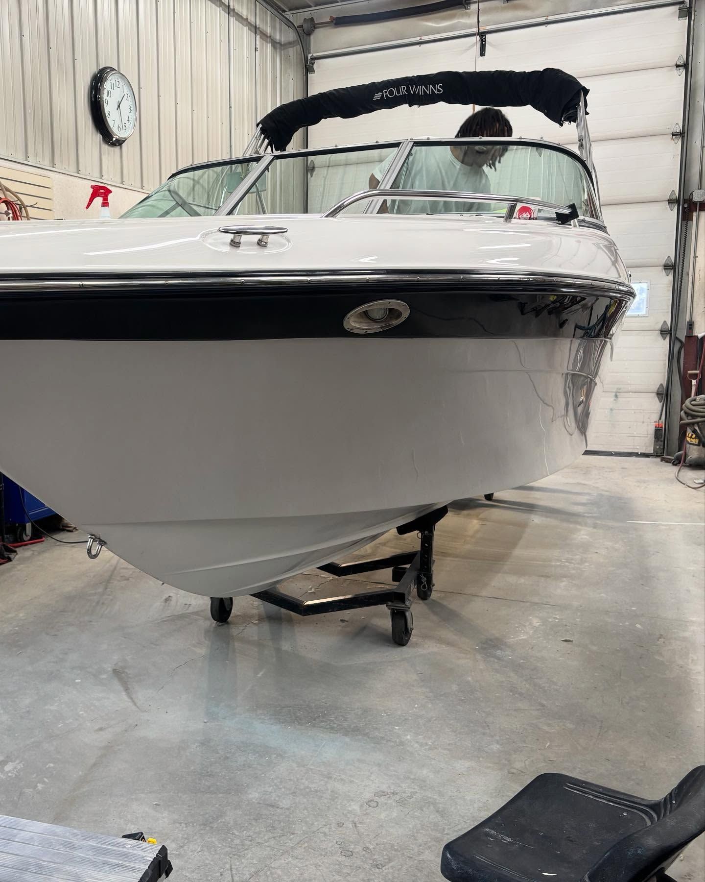 A white boat is parked in a garage next to a garage door.