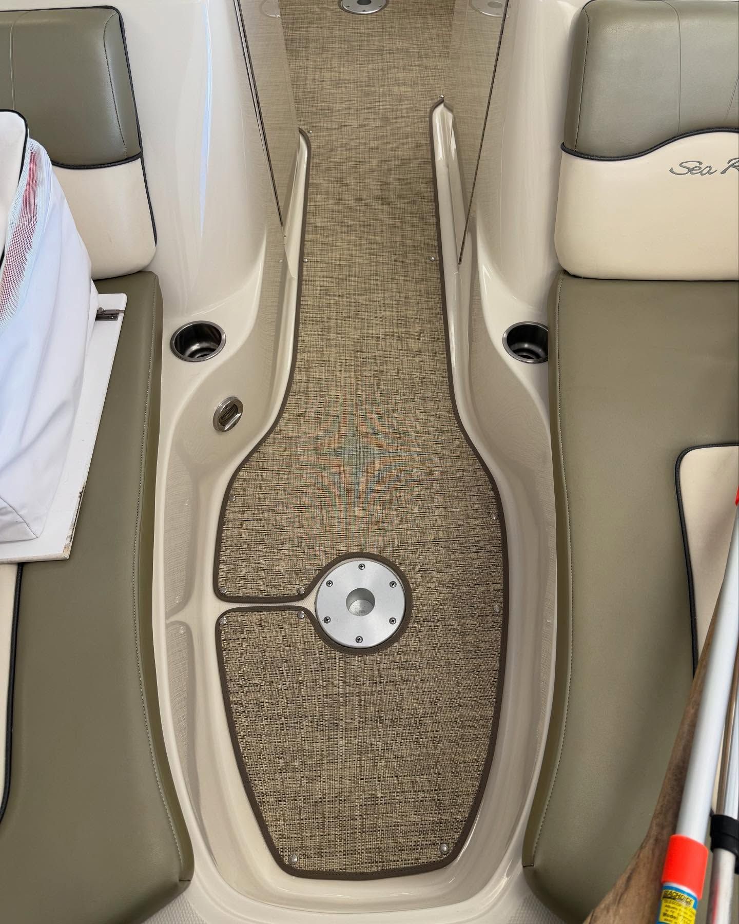 The inside of a boat with a carpeted floor and a drain.