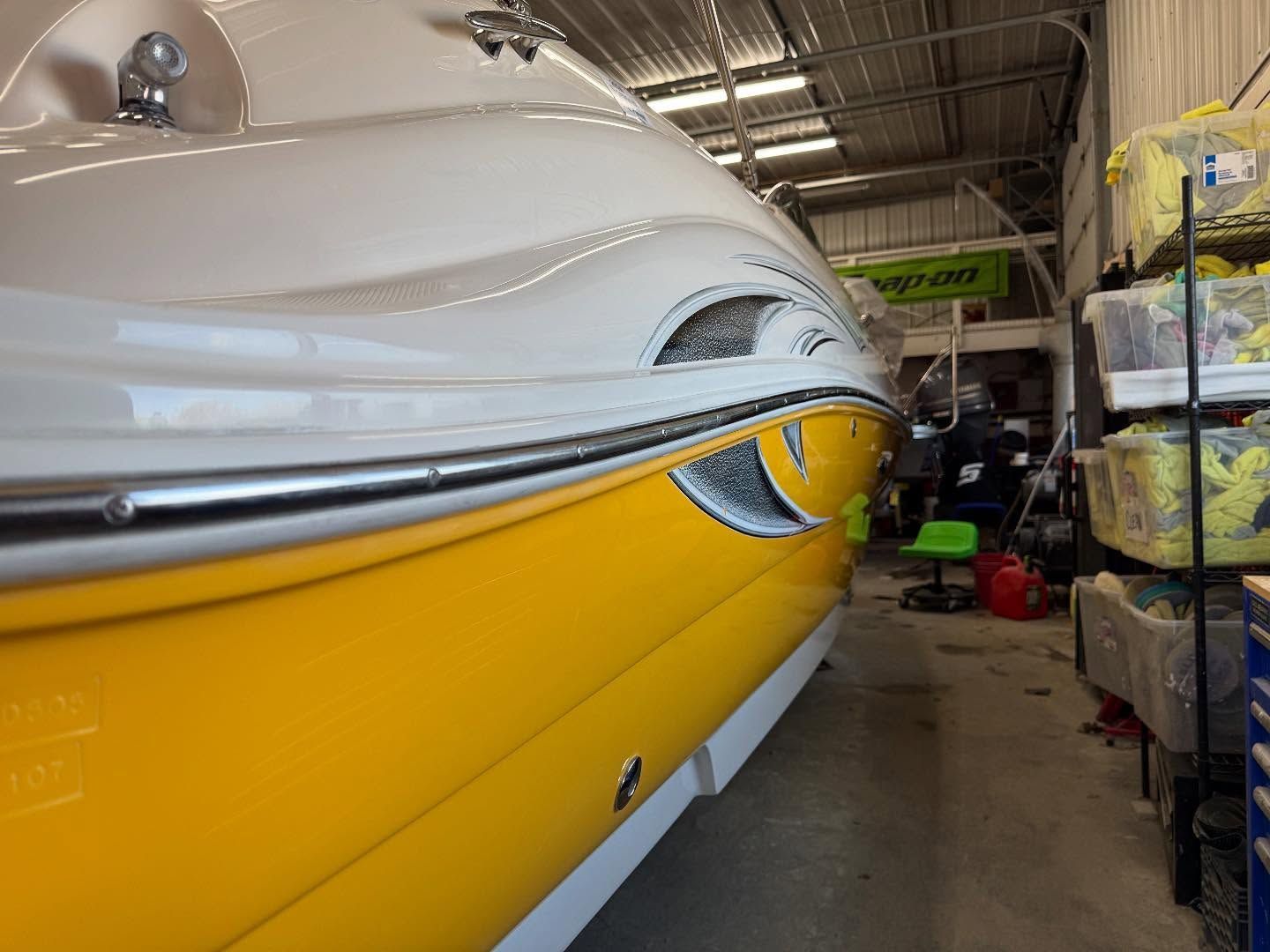 A yellow and white boat is sitting in a warehouse.