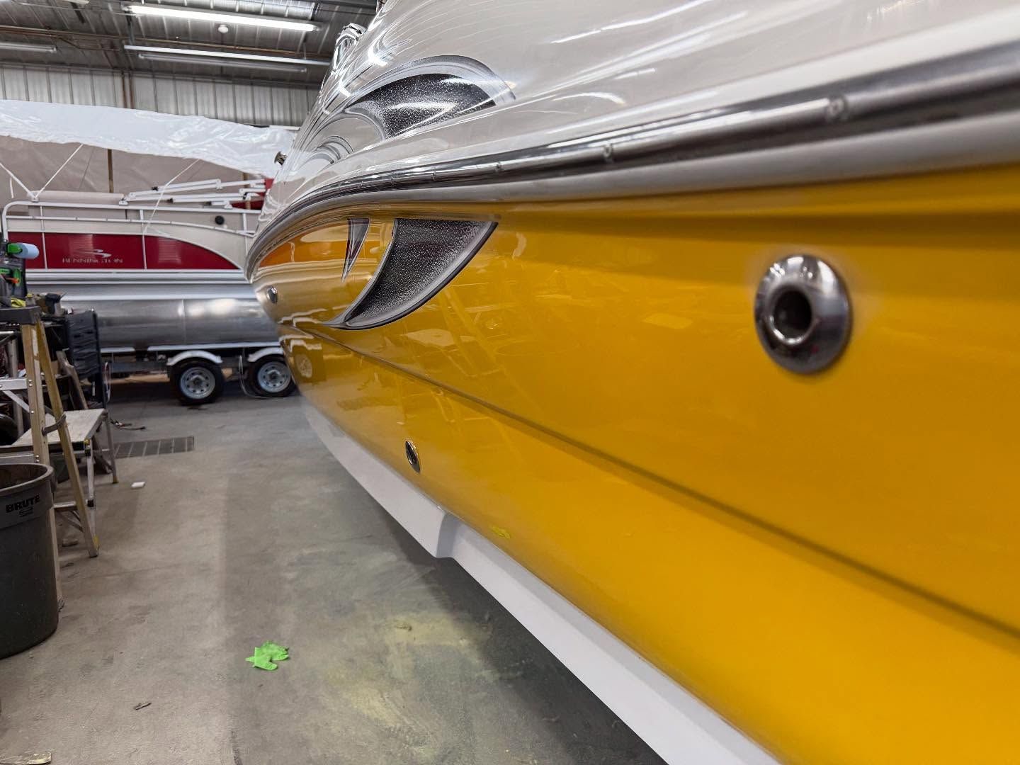 A yellow and white boat is sitting in a garage.