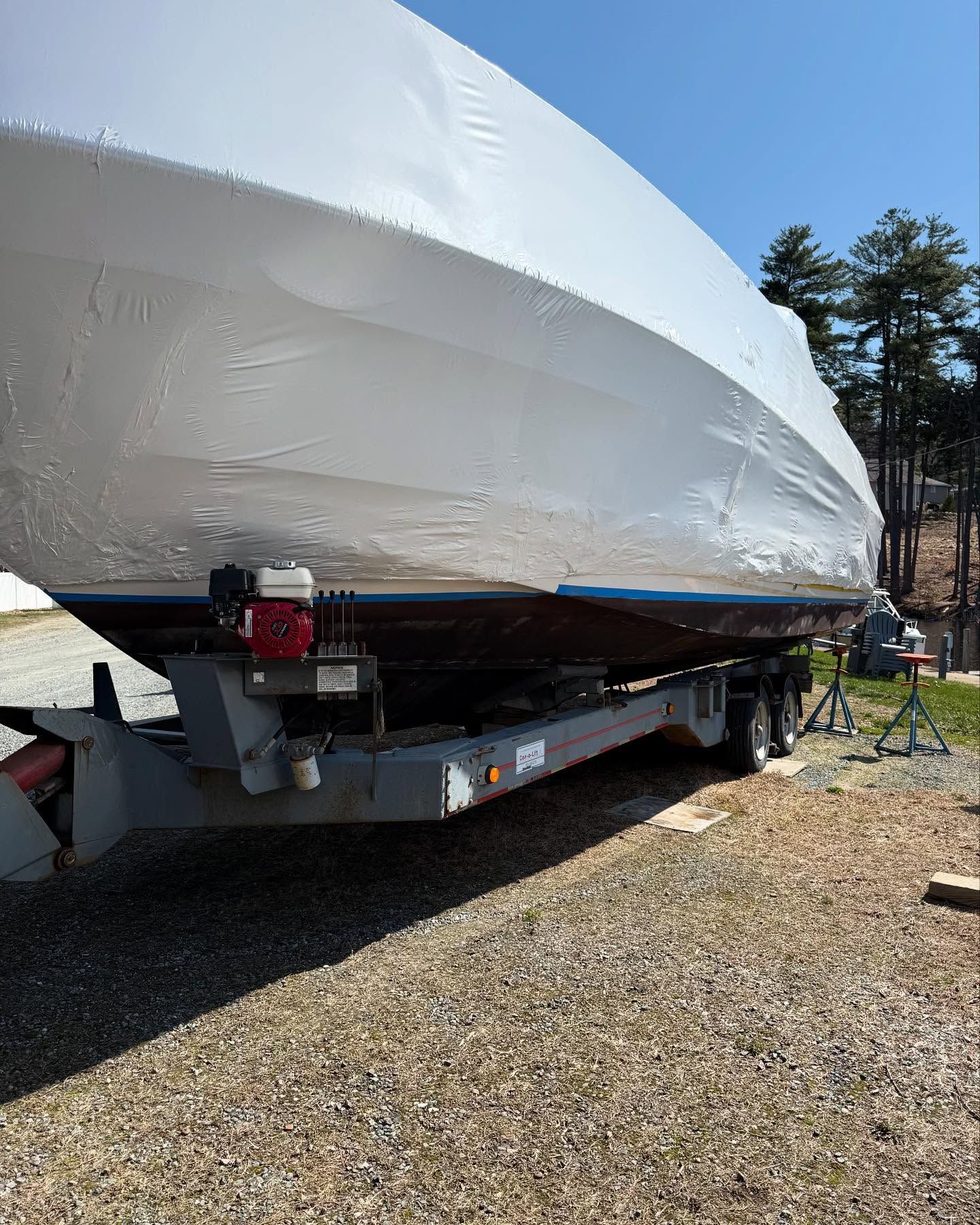 A boat is sitting on top of a trailer on a gravel road.