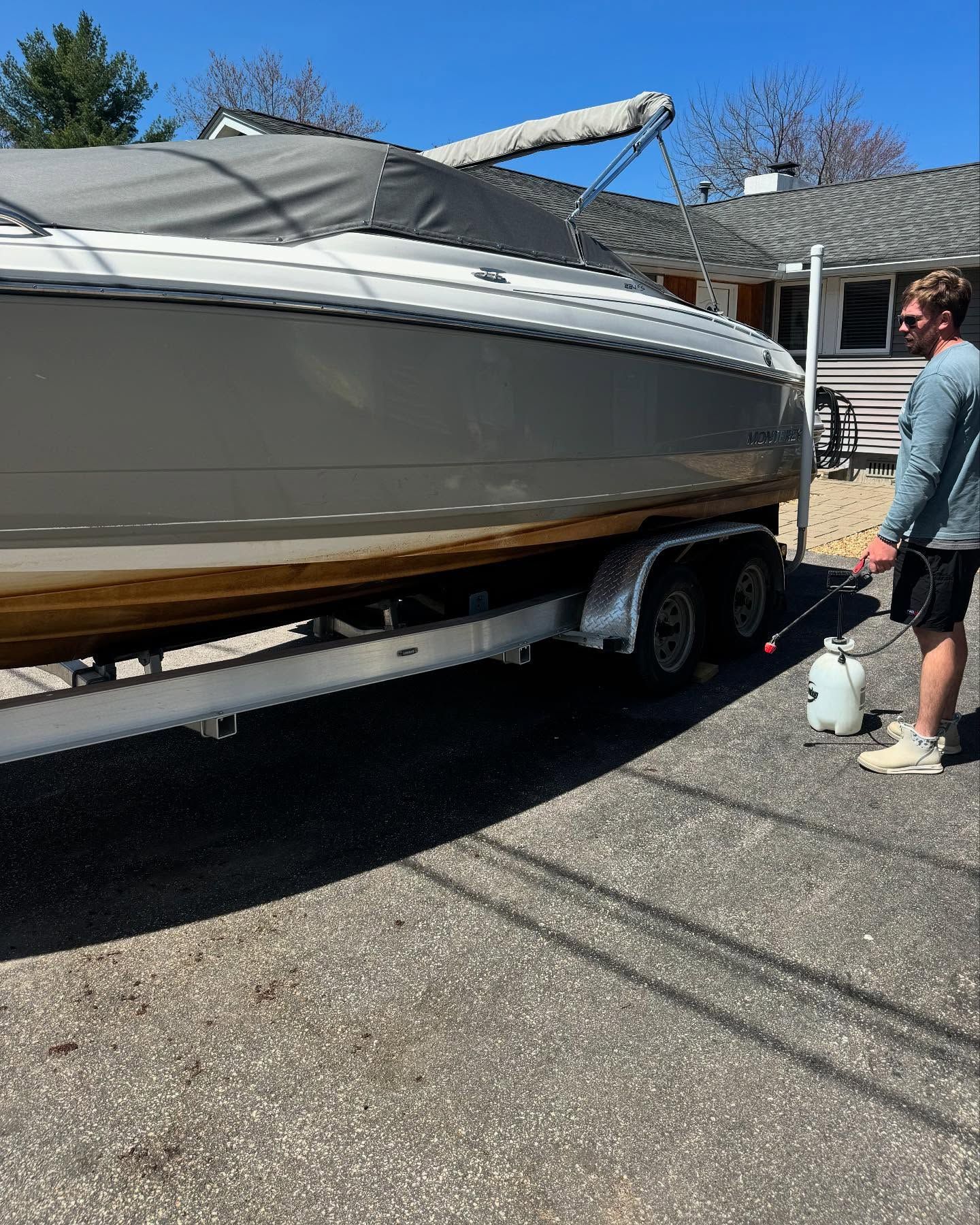 A man is standing next to a boat on a trailer.