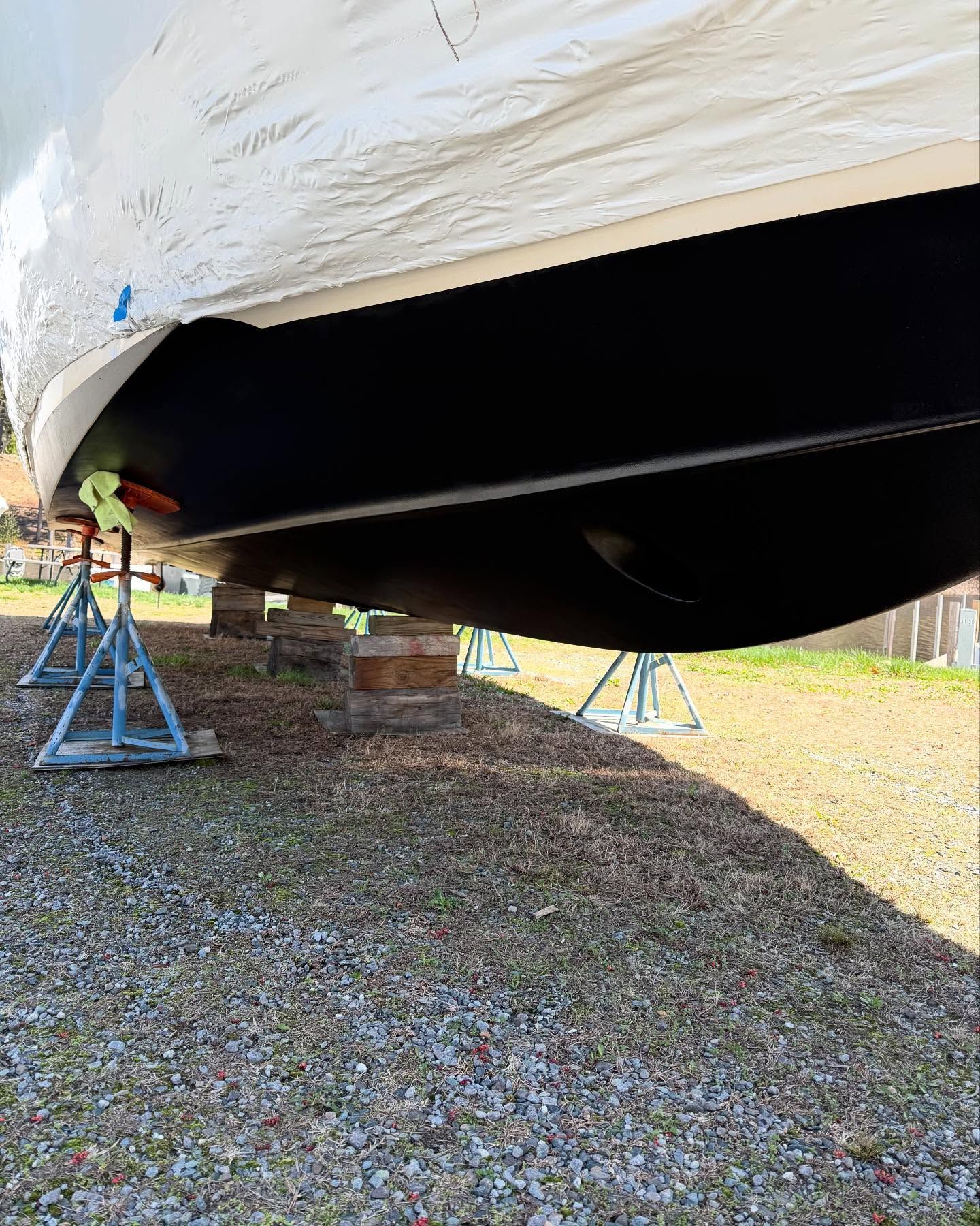 The bottom of a boat is sitting on a gravel road.
