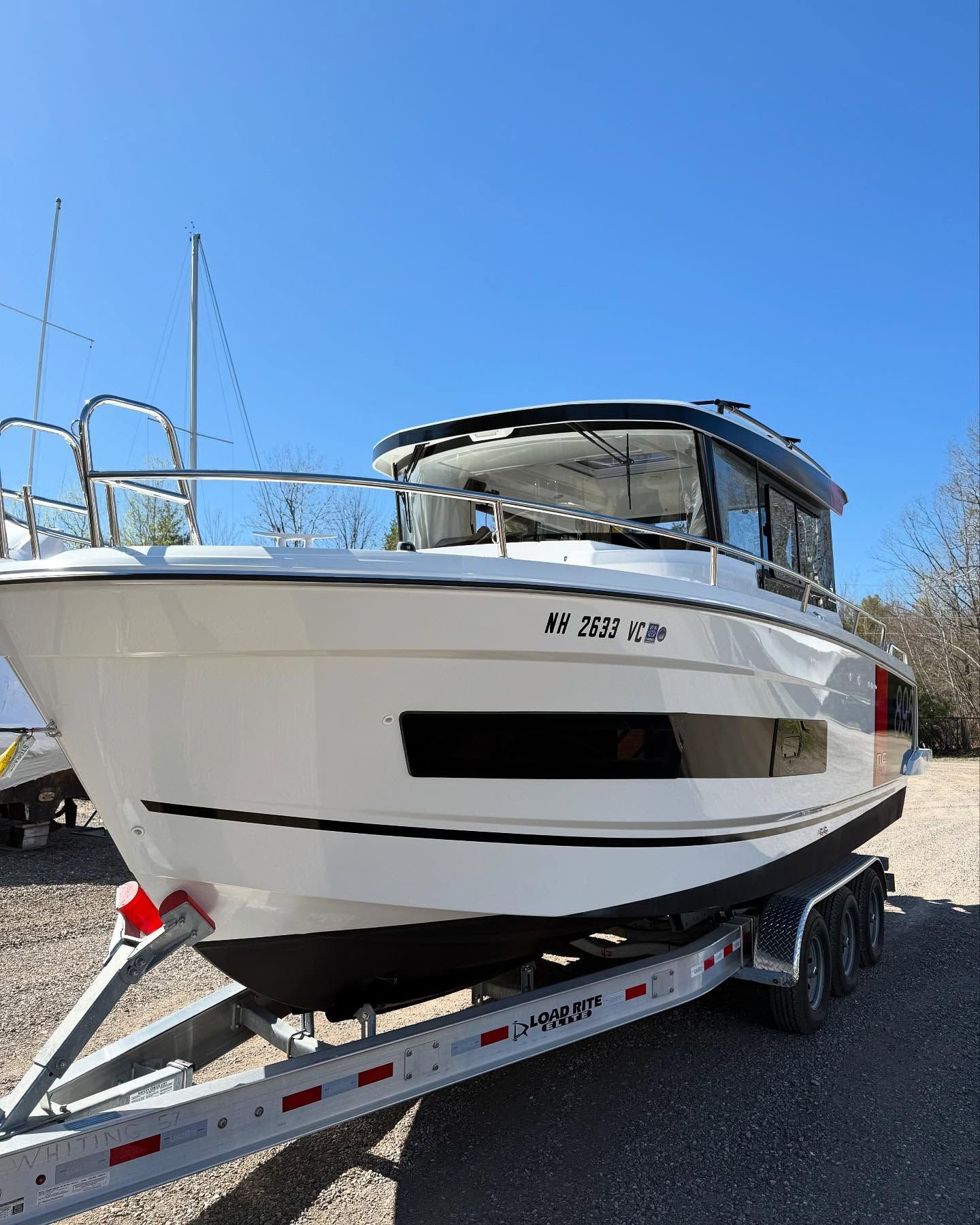 A white boat is on a trailer in a parking lot.