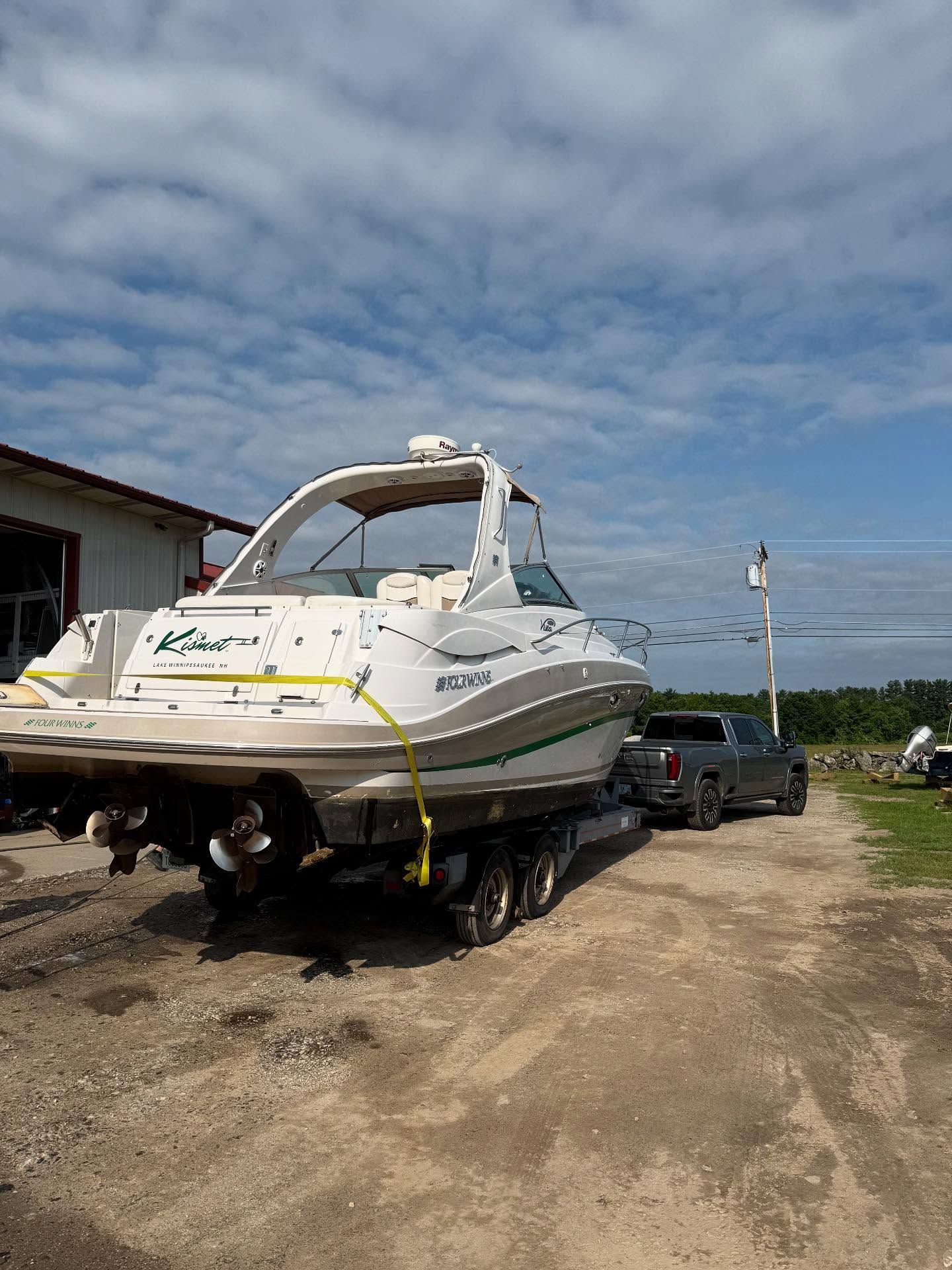 A boat is being towed down a dirt road by a truck.
