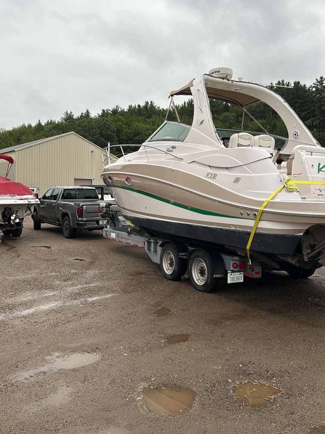 A boat is being towed by a truck in a parking lot.