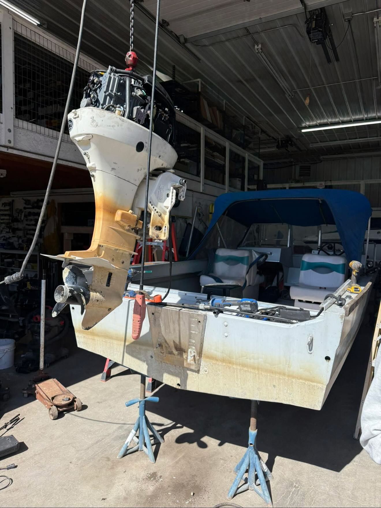 A boat with a motor hanging from the ceiling in a garage.