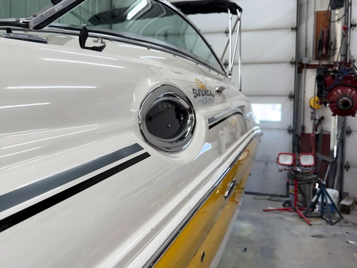 A white and yellow boat is parked in a garage.