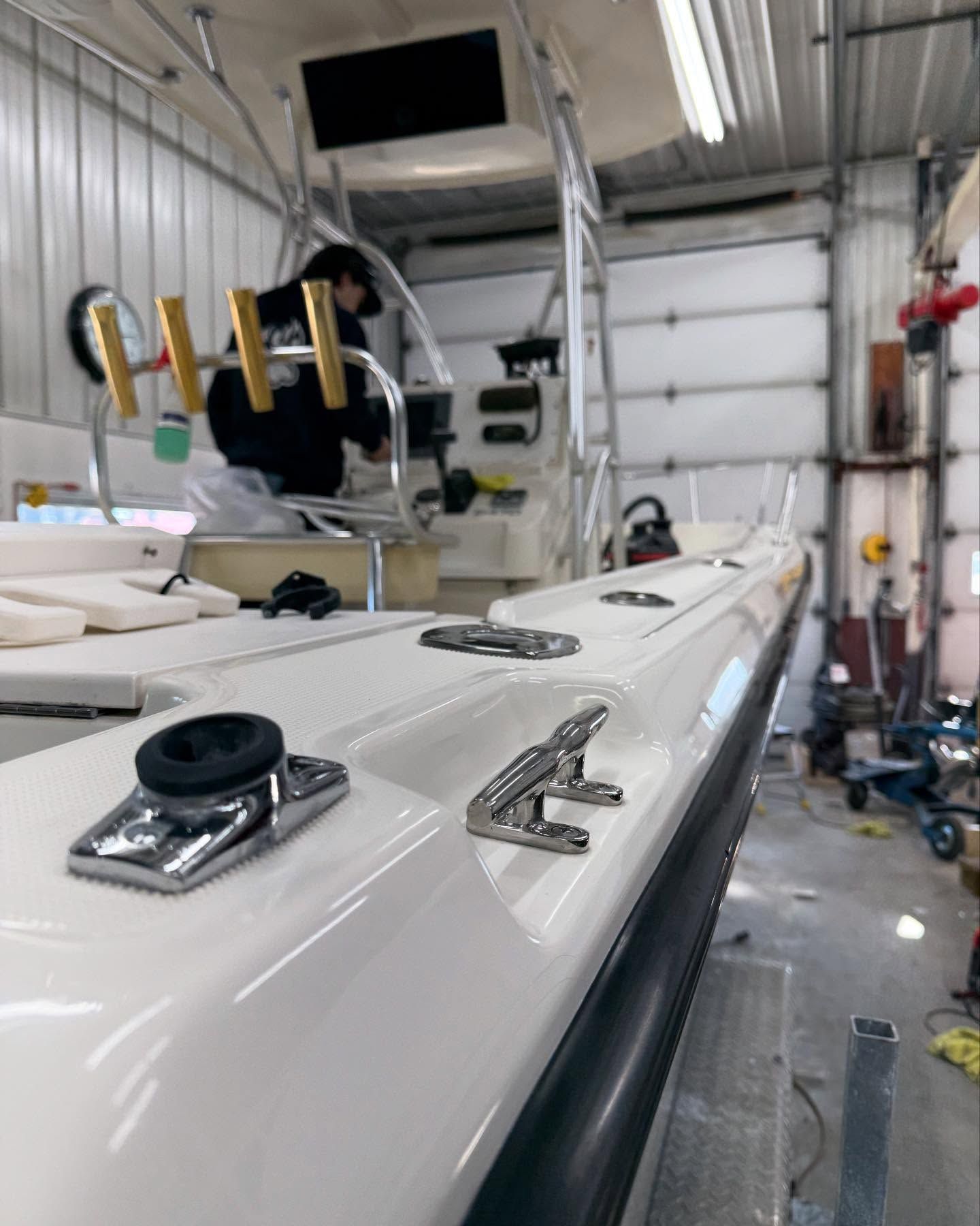 A white boat is sitting in a garage next to a garage door.