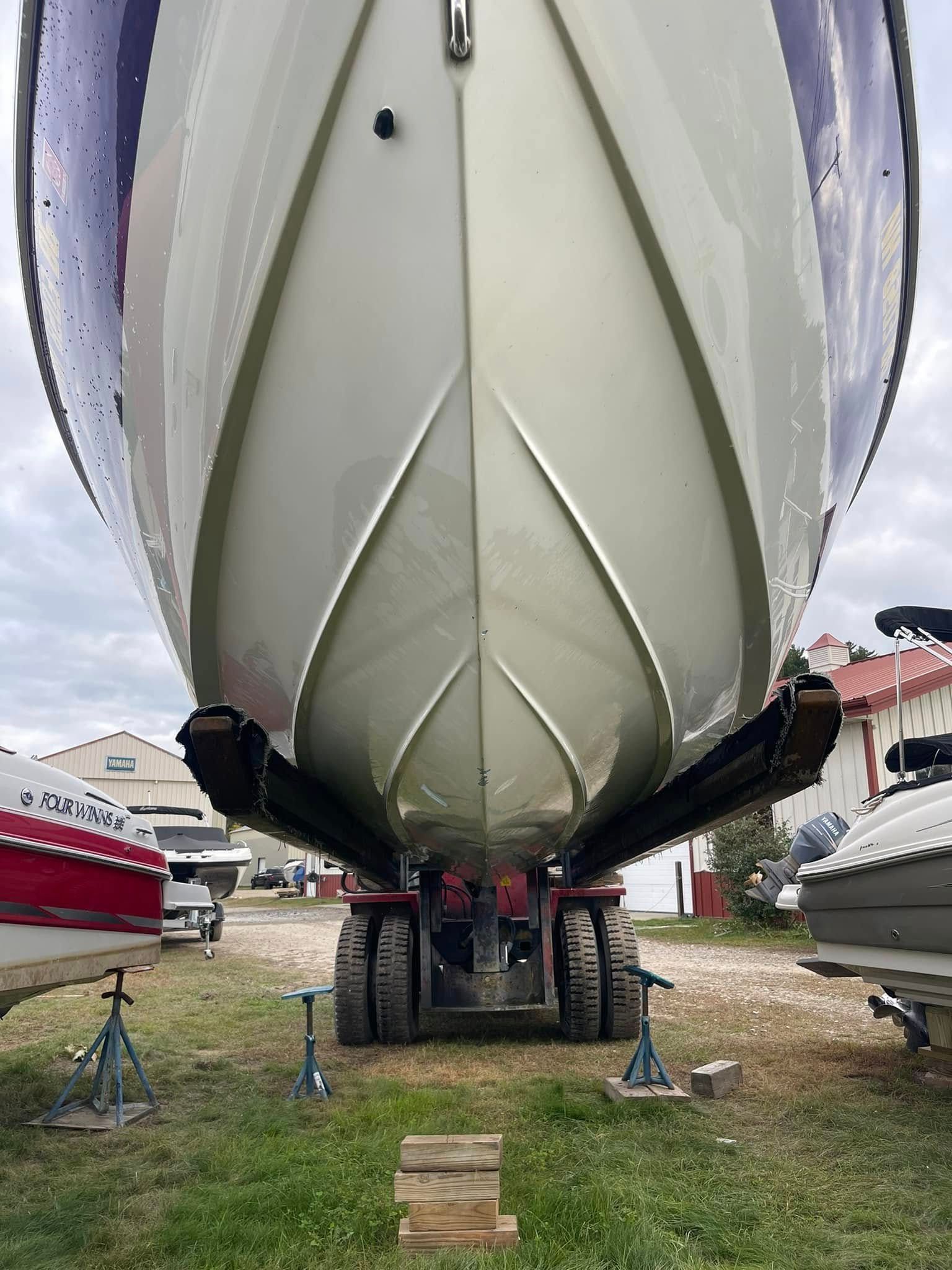 A boat is sitting on a trailer in a grassy area.