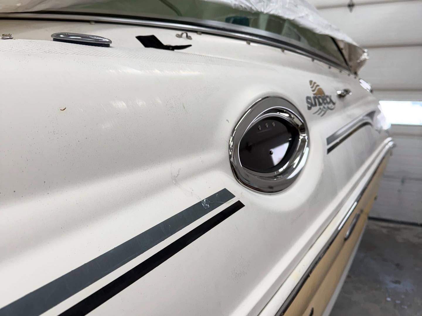 A white boat with black stripes on the side is parked in a garage
