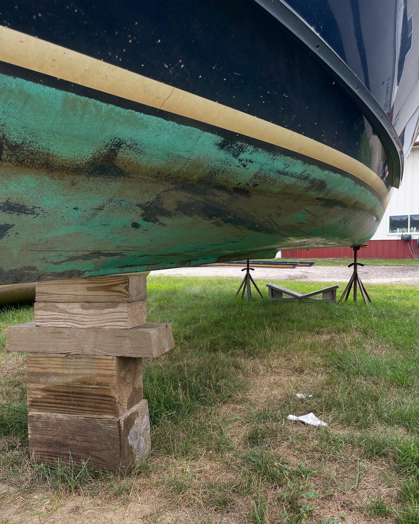 A boat is sitting on a wooden block in the grass.
