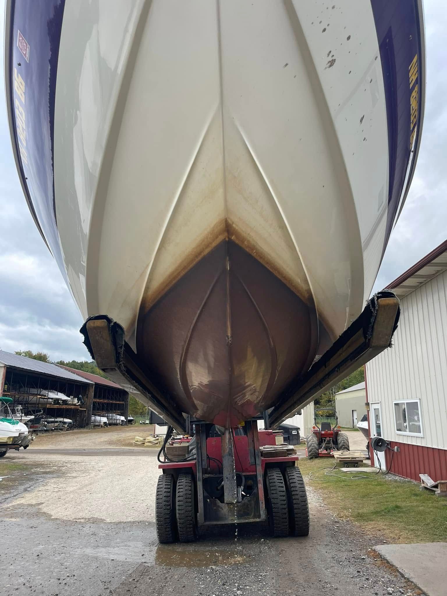 A boat is being lifted by a tractor in a parking lot.