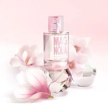 A bottle of perfume is surrounded by pink flowers on a pink background.