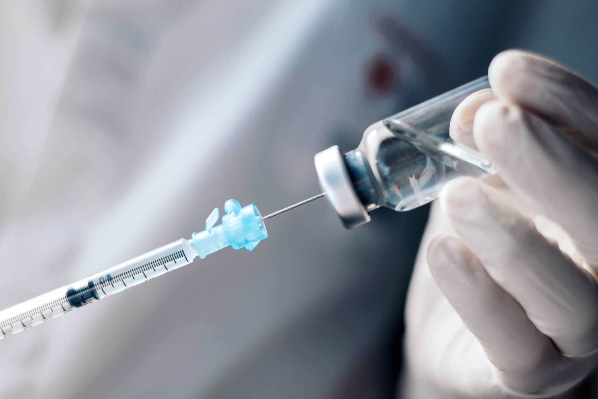 A person is holding a syringe and a bottle of vaccine.