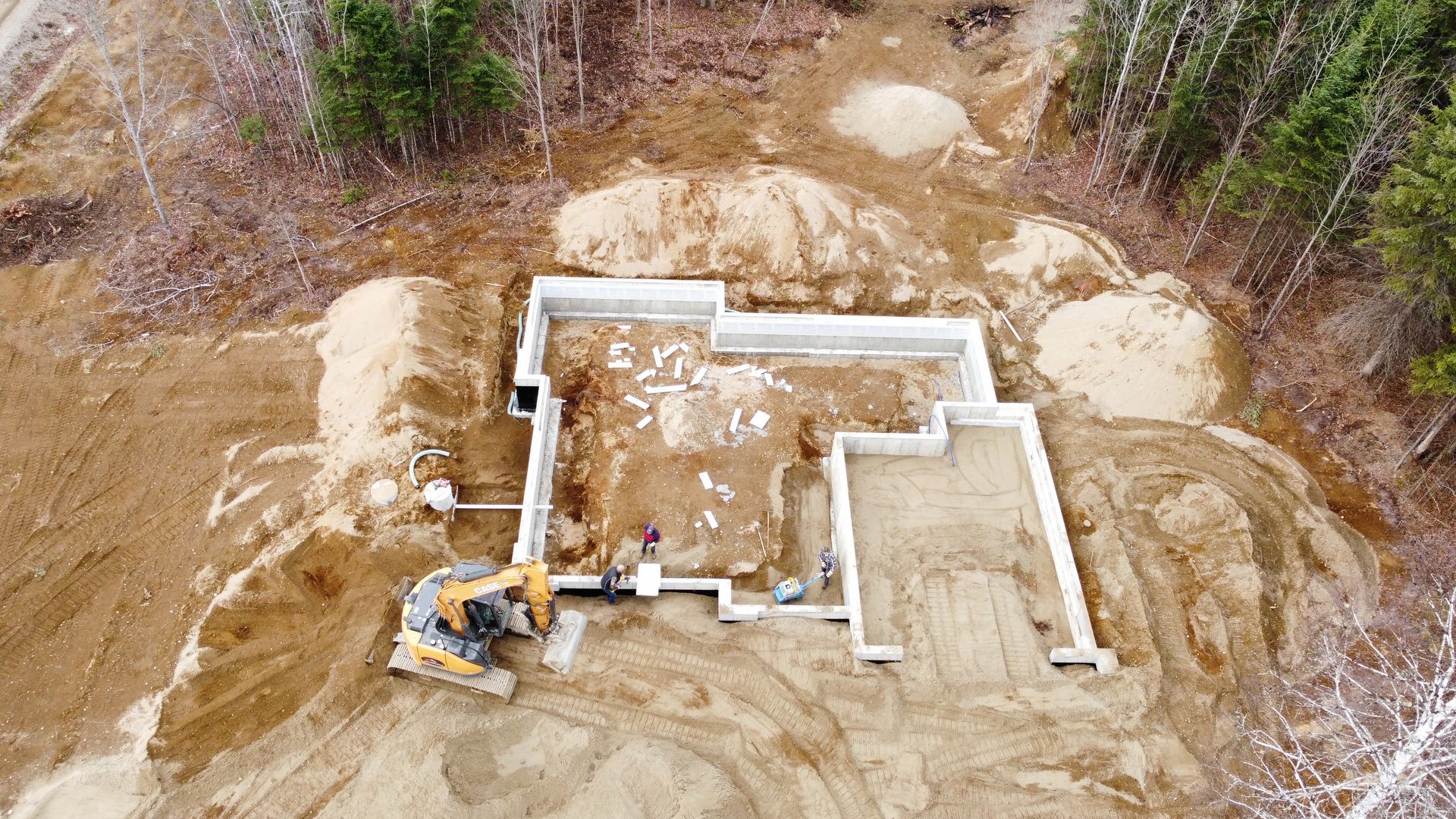 Vue aérienne d'une maison en construction au milieu d'une forêt.