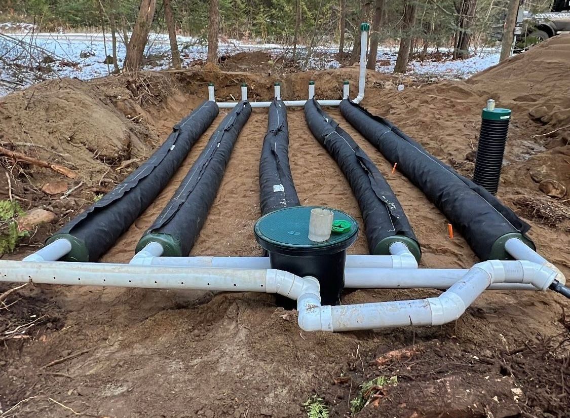 Un système septique avec plusieurs tuyaux de drainage enveloppés dans une tranchée ouverte.