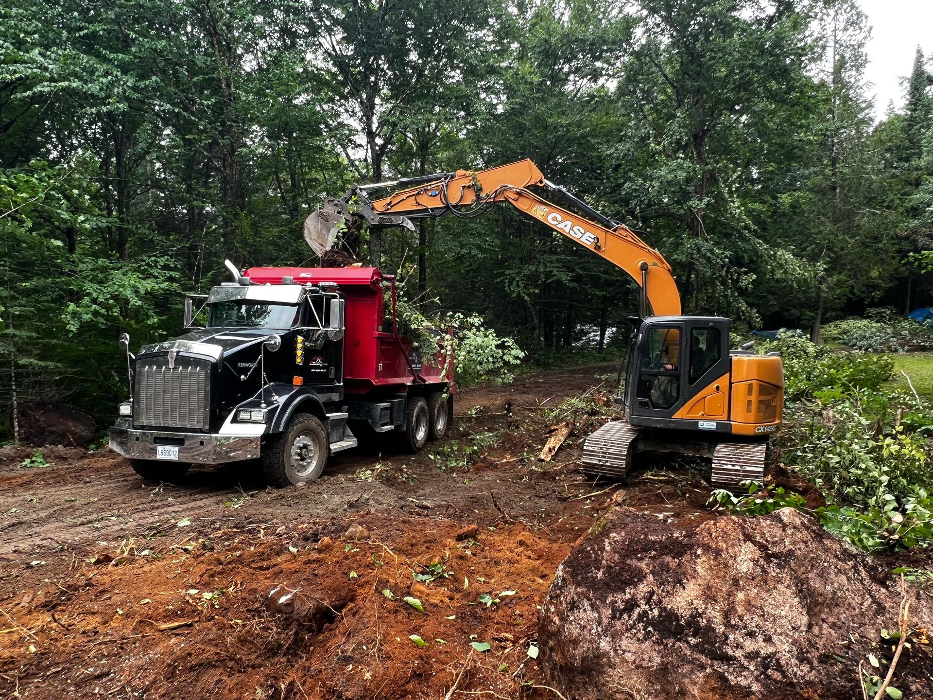 Un camion-benne et une excavatrice traversent un champ de terre.