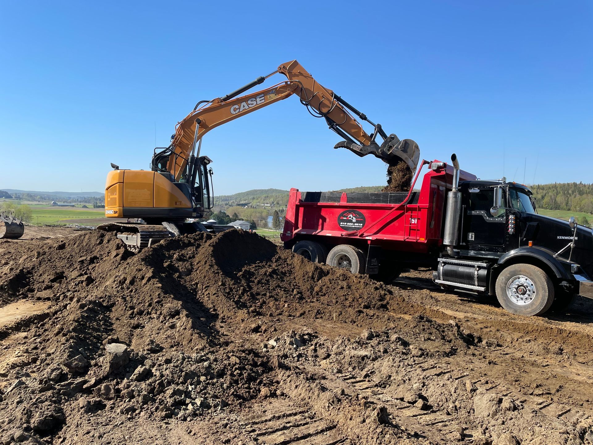 Une excavatrice charge de la terre dans un camion-benne.