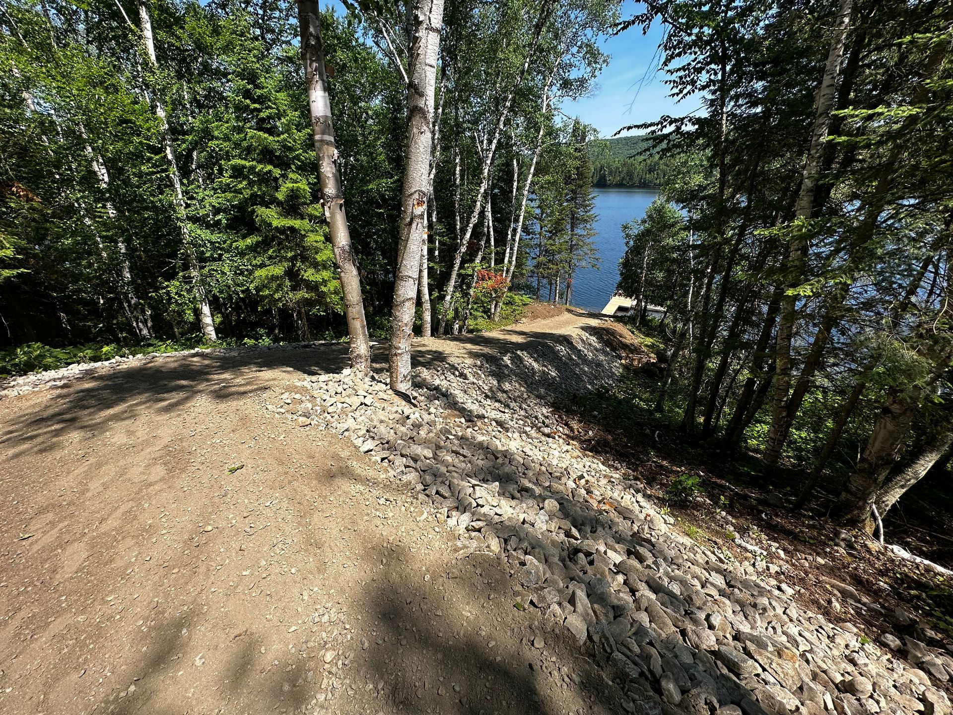 Un chemin de terre menant à un lac entouré d'arbres.