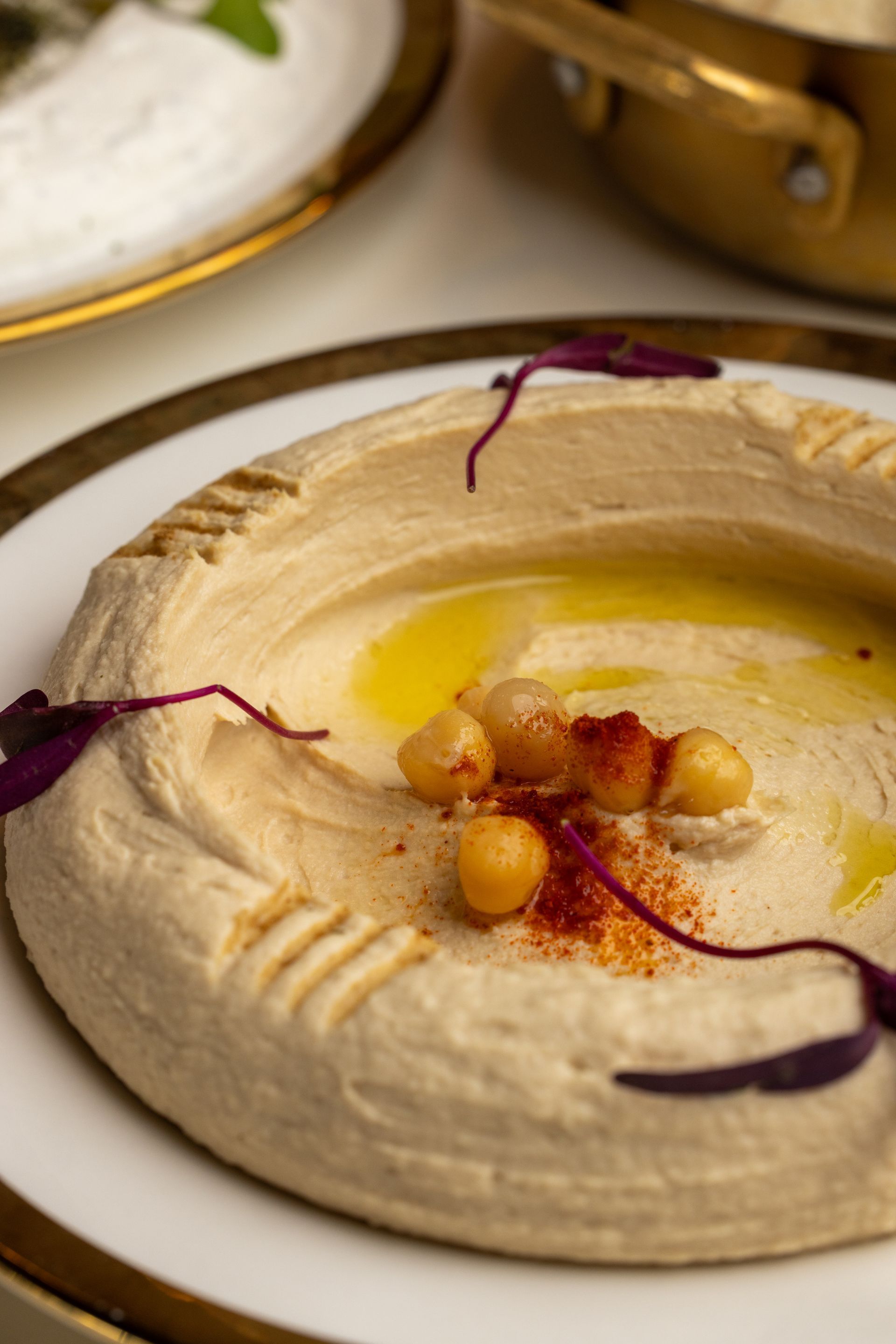 Hummus on a white plate, drizzled with olive oil, chickpeas, and paprika.