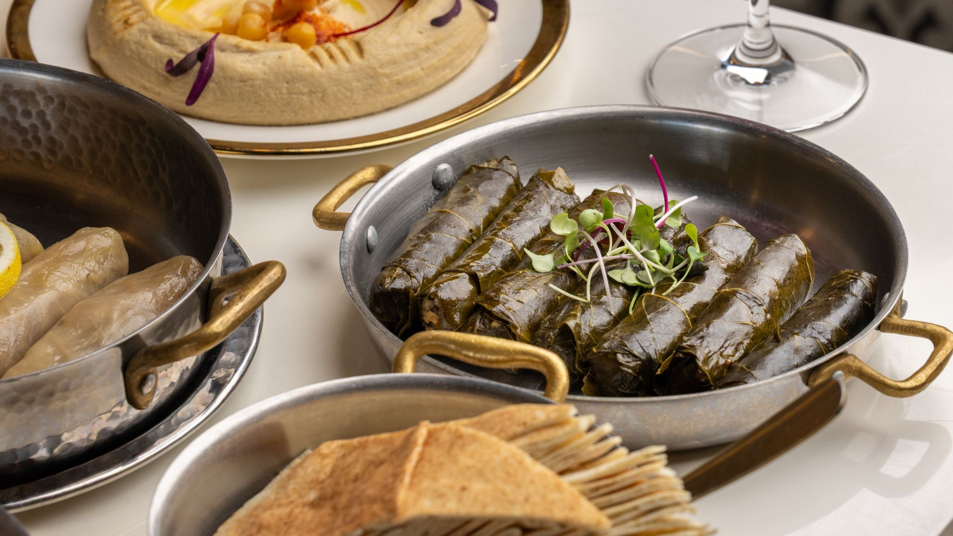 Several dishes of food, including stuffed grape leaves, in metal serving dishes.