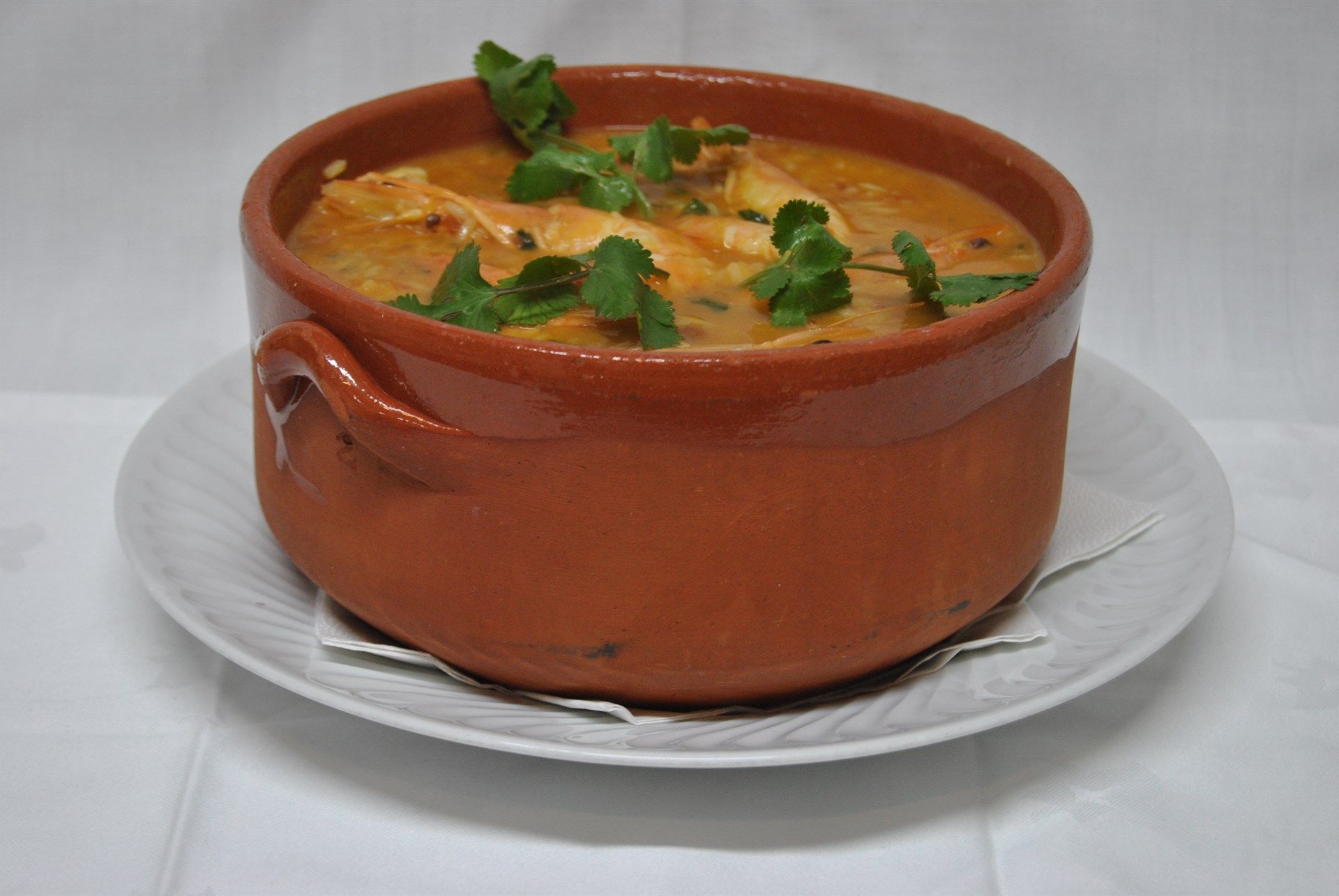 Uma tigela de sopa em um prato branco sobre uma mesa