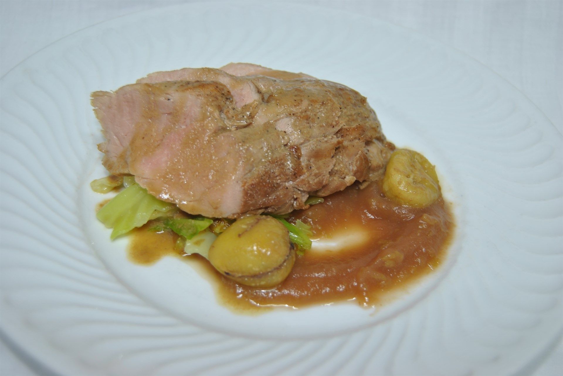 Um prato branco coberto com carne e molho sobre uma mesa