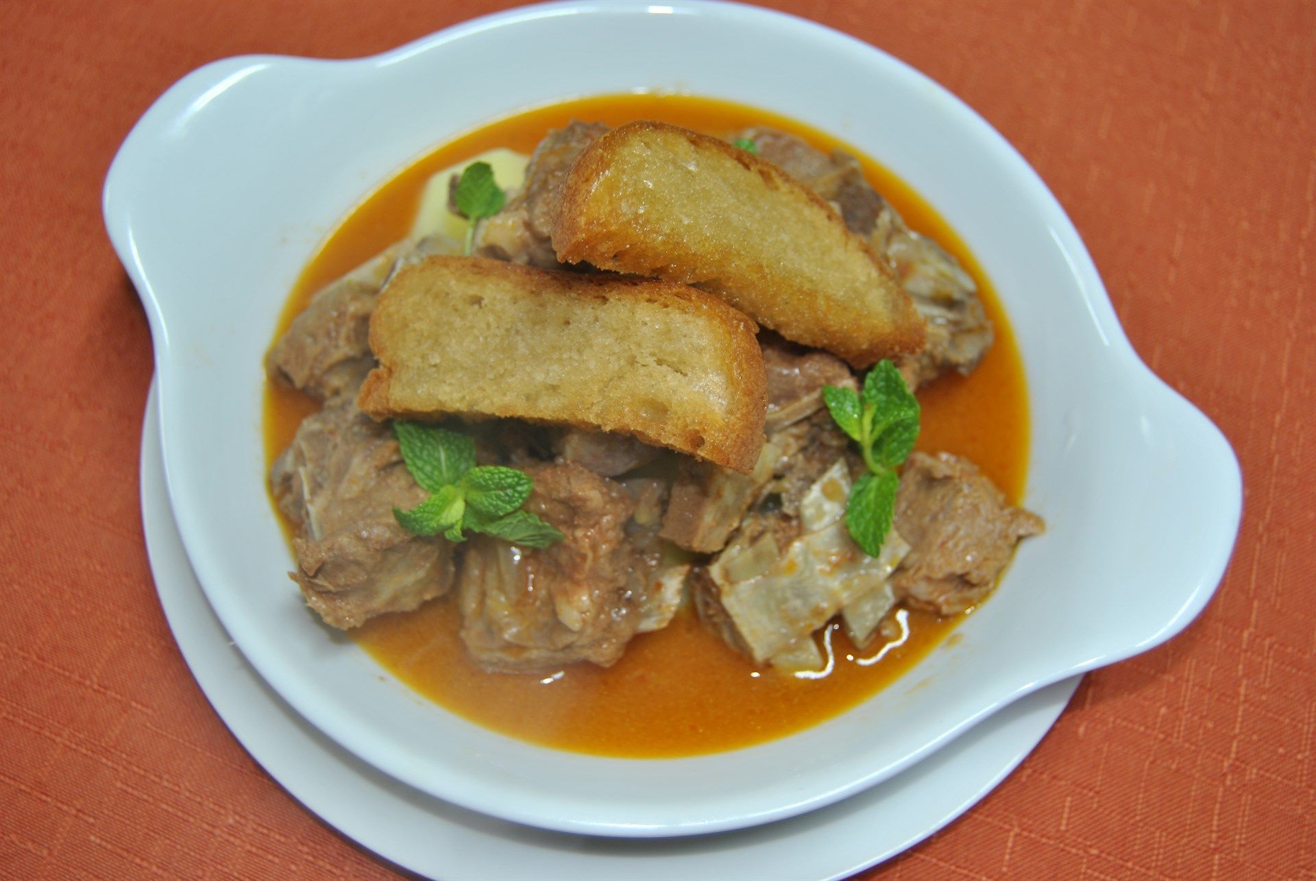 Uma tigela branca cheia de carne e molho sobre uma mesa