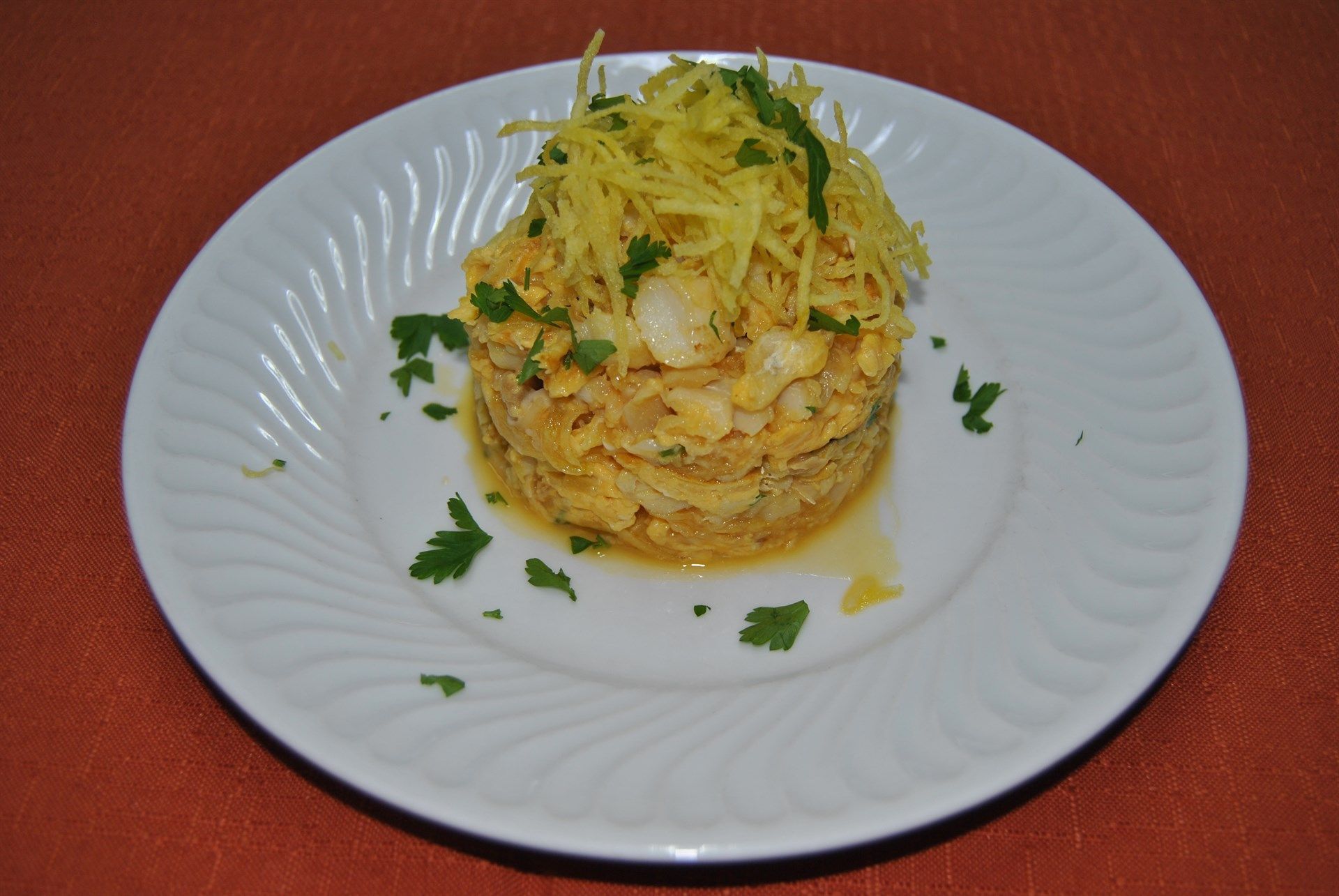 Um prato branco com uma pilha de comida em cima