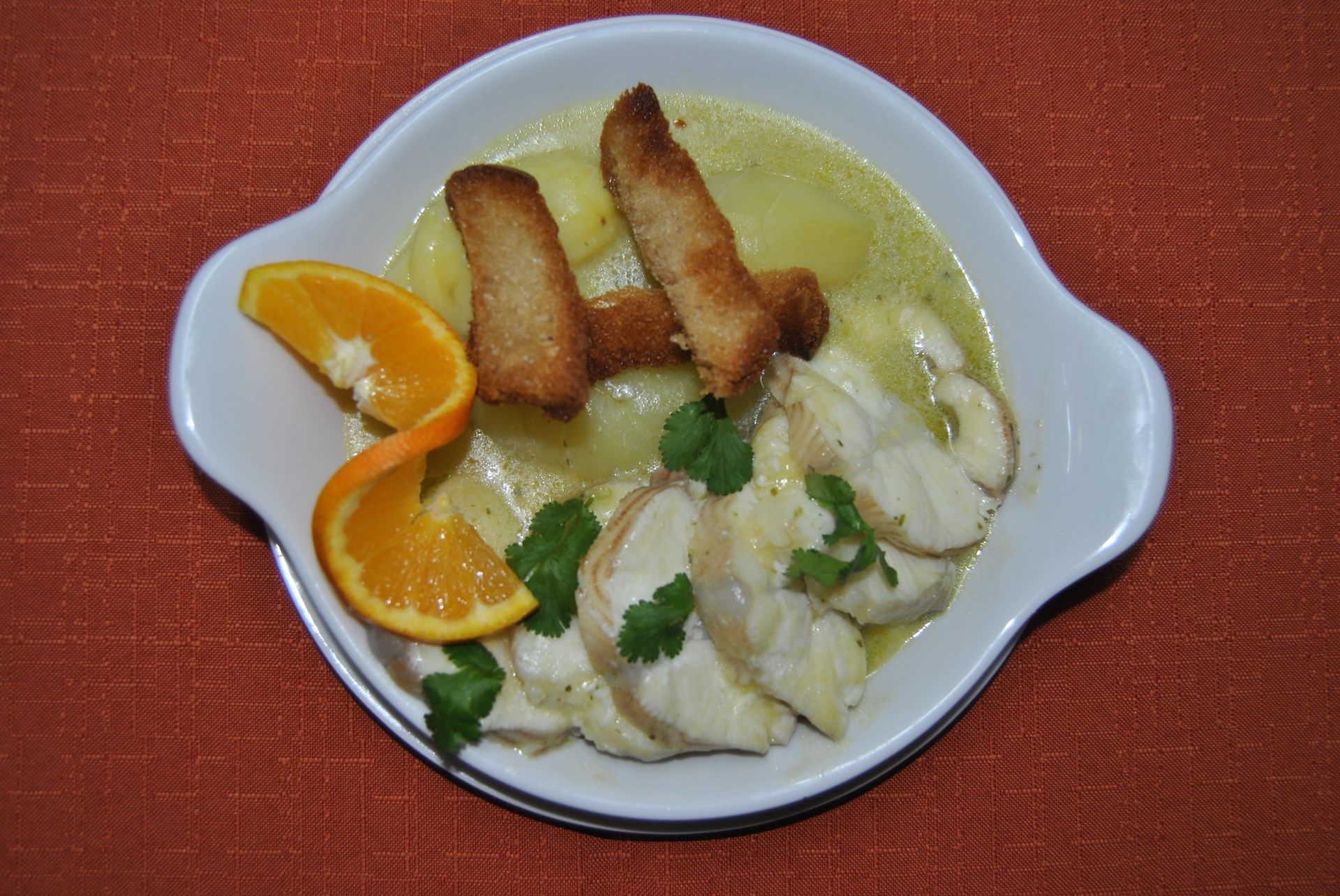 Um prato de comida com palitos de pão e laranjas sobre uma mesa.
