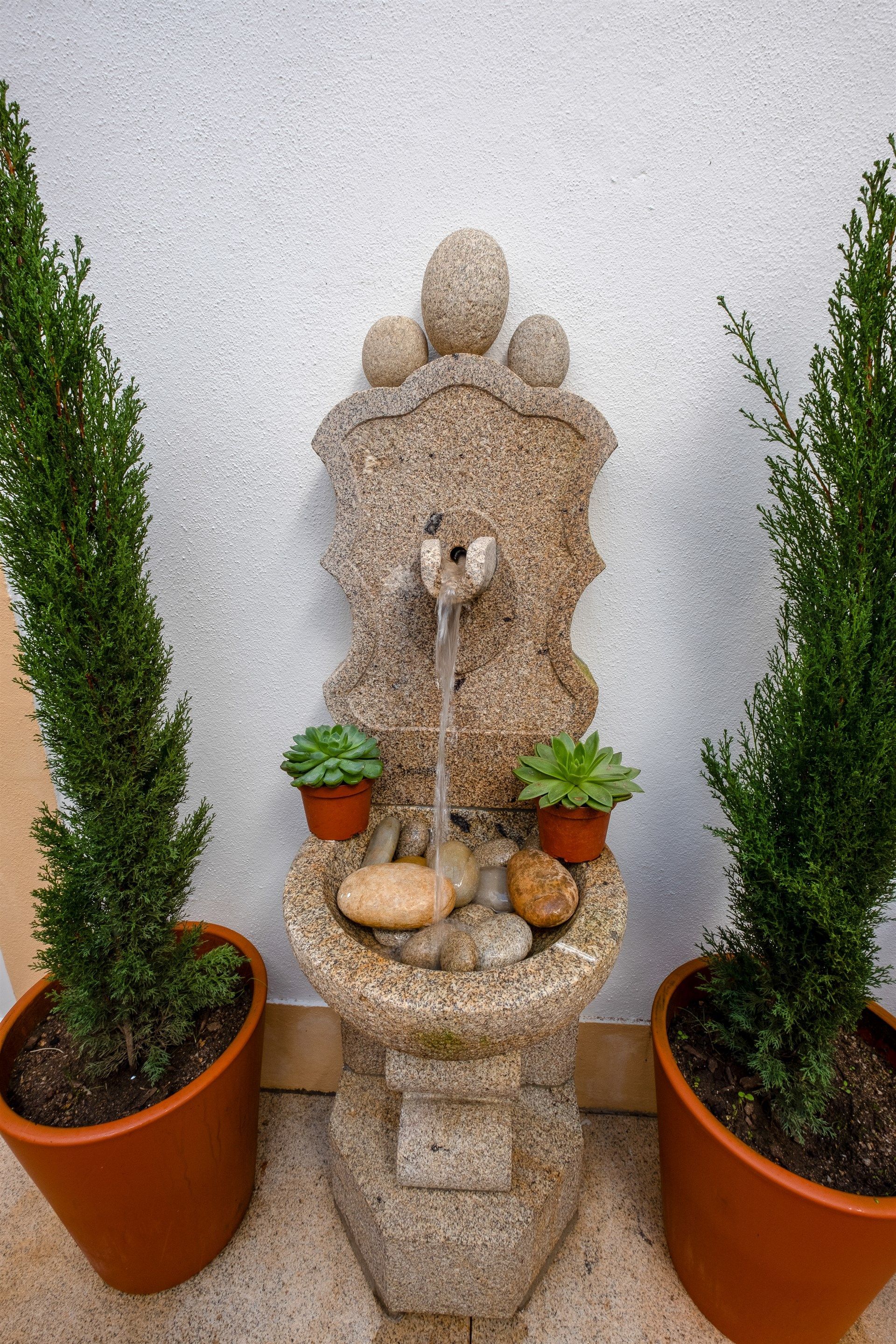 Uma fonte com dois vasos de plantas ao lado