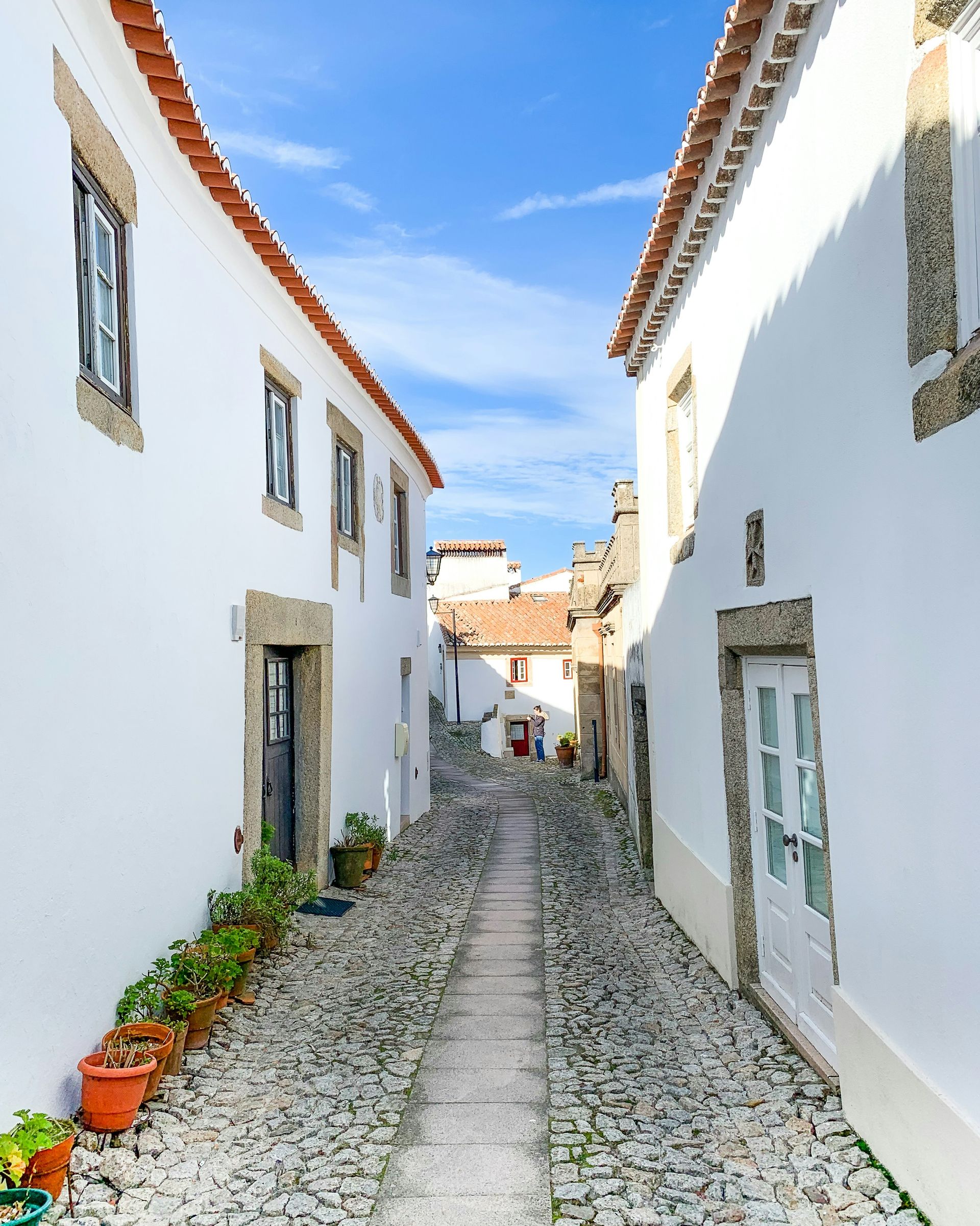 Uma rua estreita de paralelepípedos entre dois prédios brancos