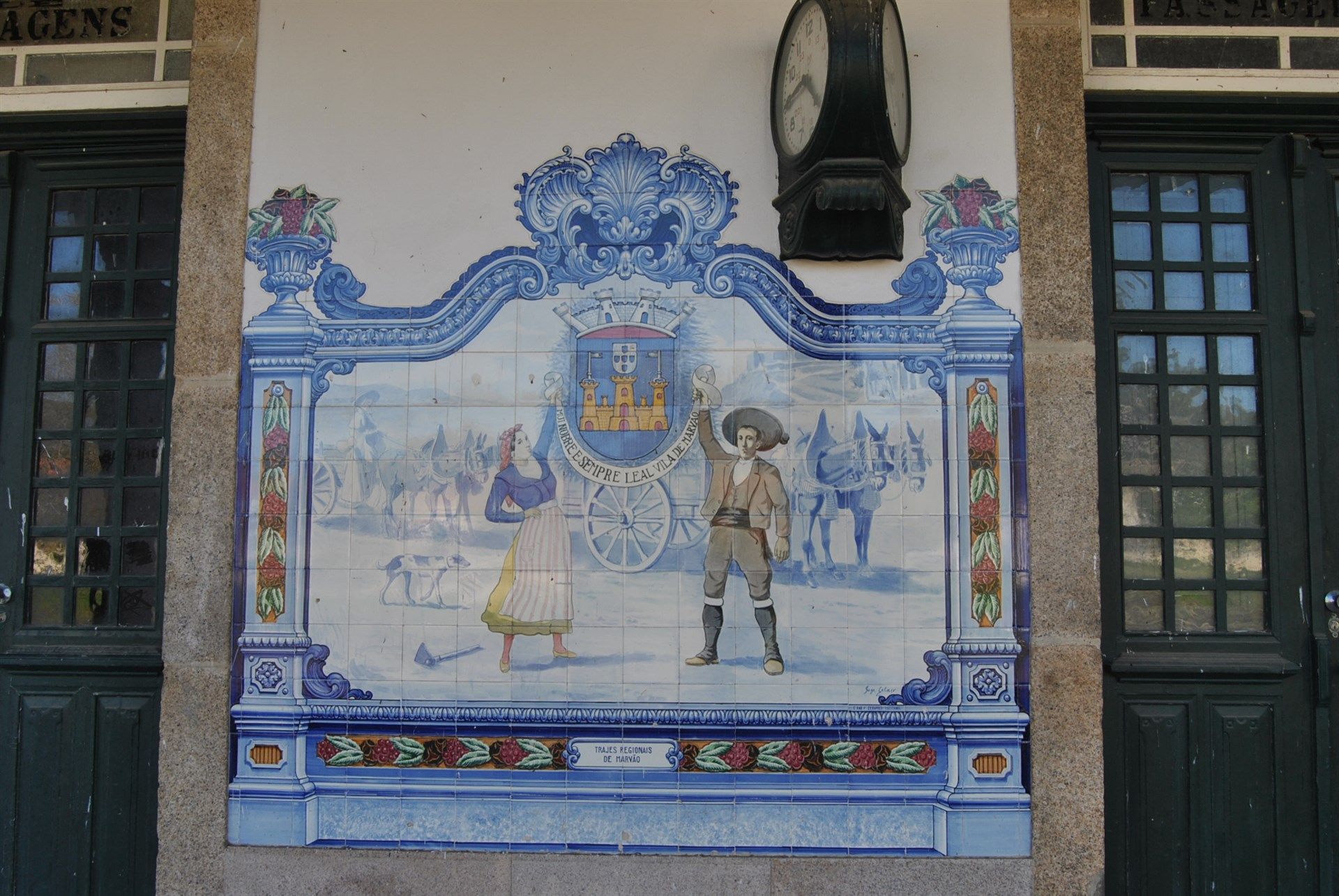 Um relógio pendurado sobre uma pintura de um homem e uma mulher Marvão 