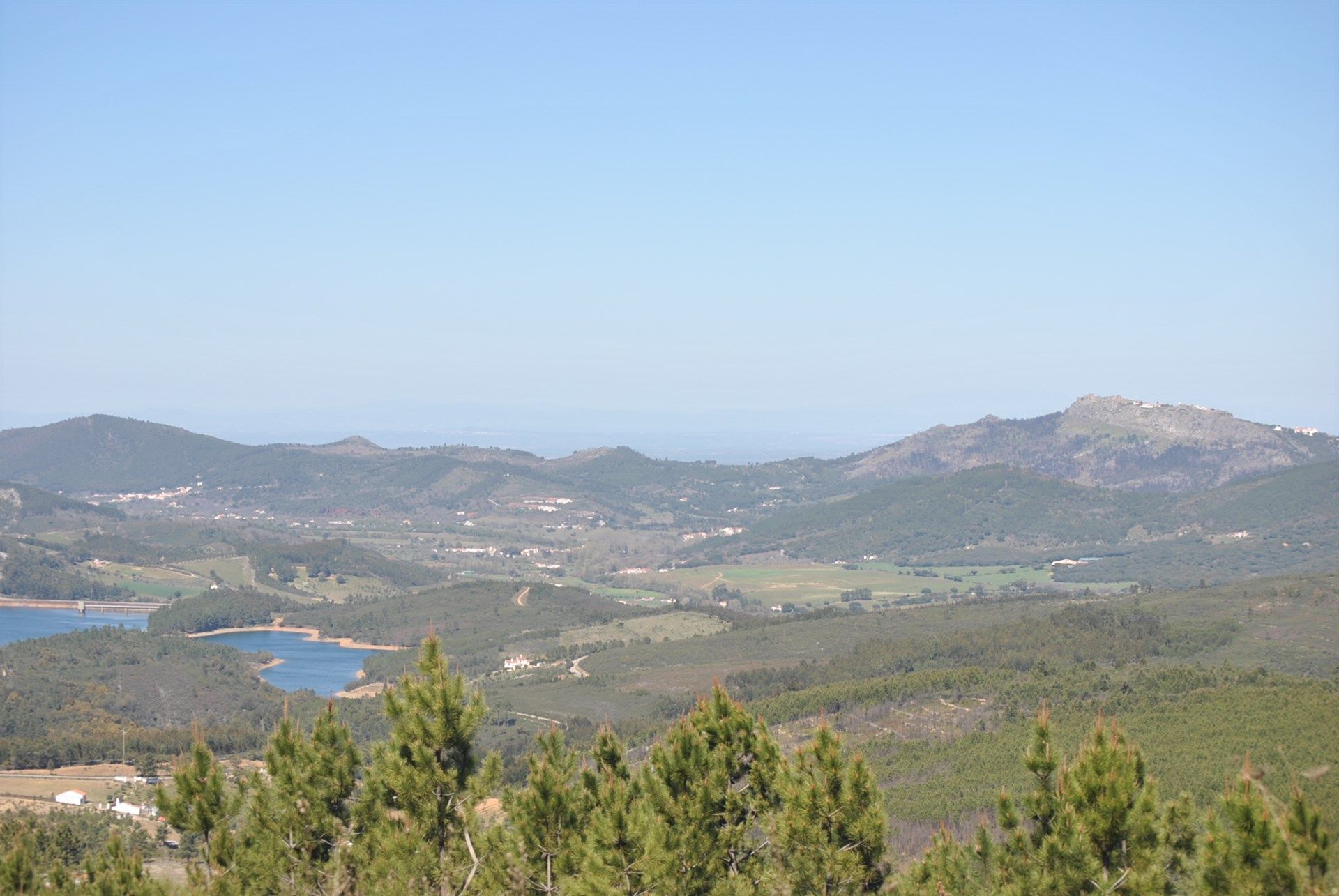 Uma vista de um lago cercado por montanhas e árvores