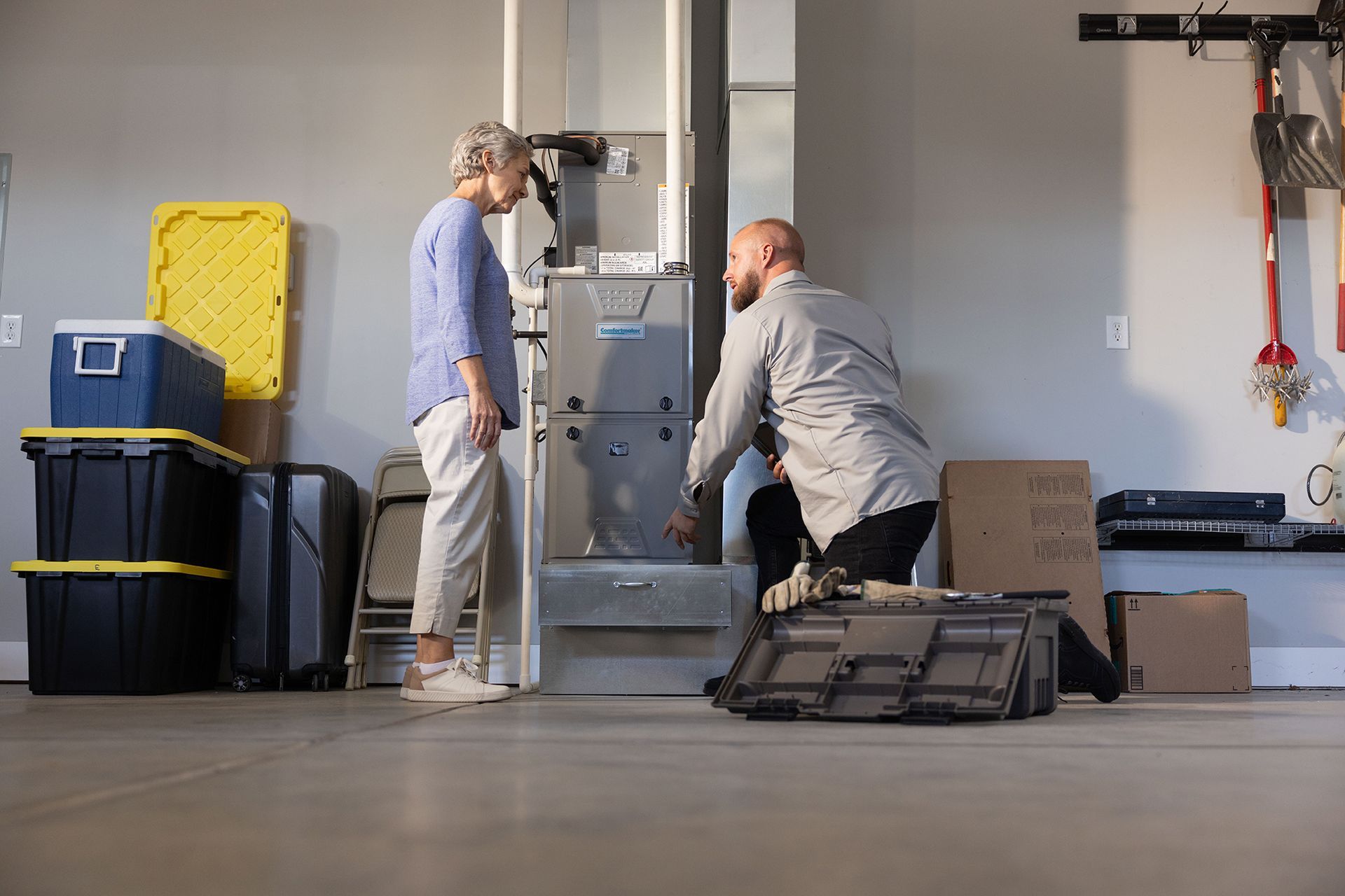 Man in gray shirt writing on clipboard in a kitchen; smiling, leaning on countertop.