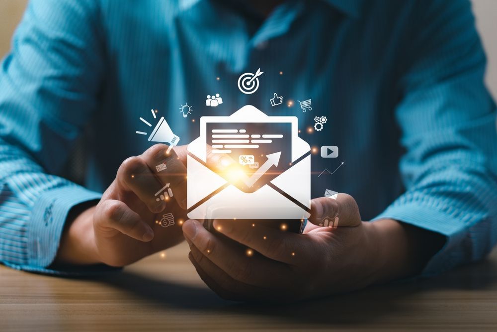 Person holding an illuminated email envelope with digital marketing icons, suggesting email campaign.