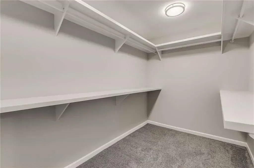 An empty walk in closet with shelves and a light on the ceiling.