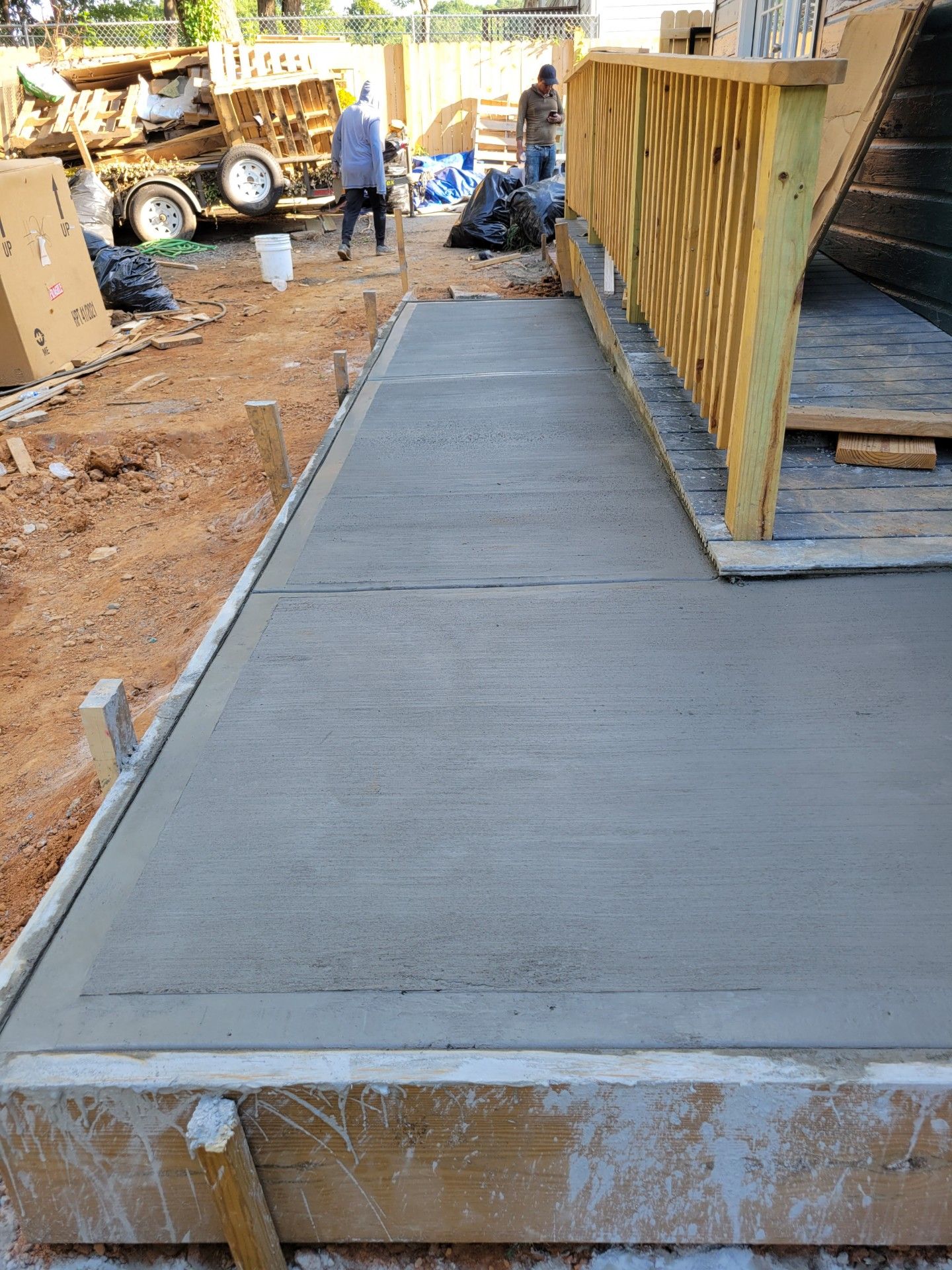 A concrete walkway is being built next to a wooden deck.