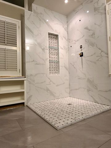 A bathroom with marble walls and a walk in shower