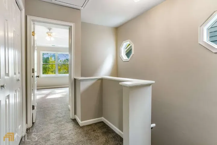 A hallway leading to a bedroom and a staircase in a house.