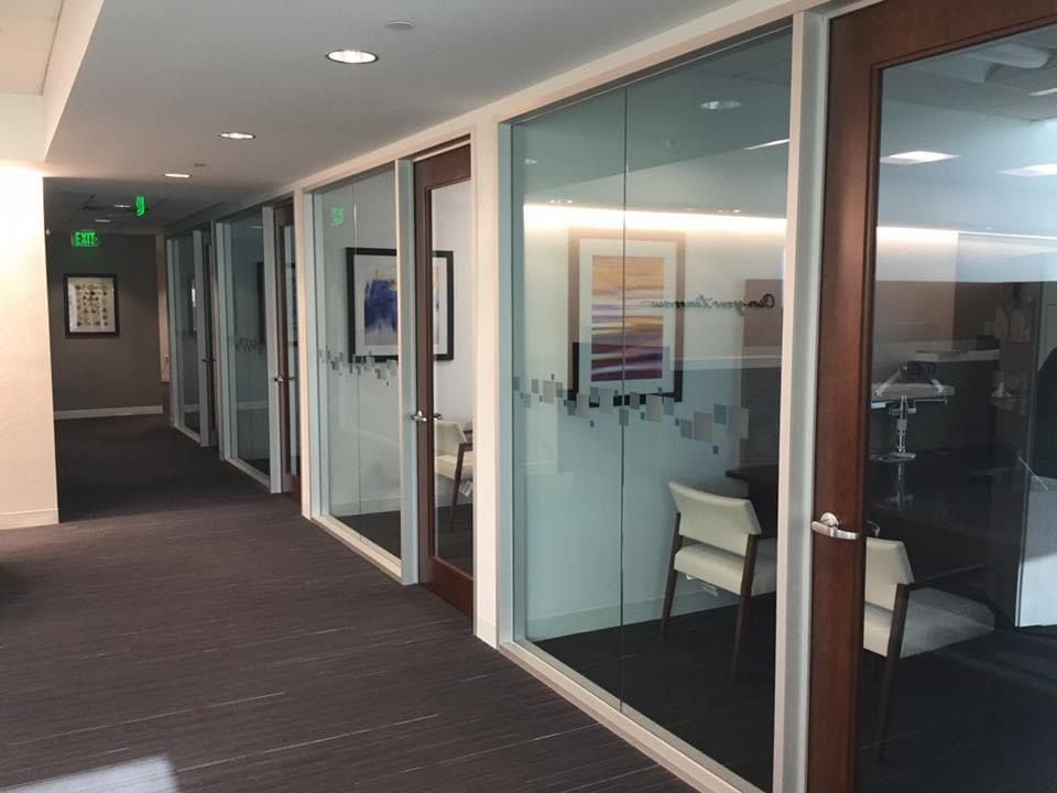 A hallway with a lot of glass doors and chairs